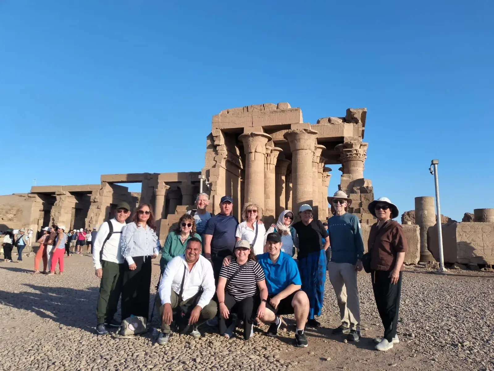 Kom Ombo Temple columns with a group of tourists posing in front during a day tour in Egypt.