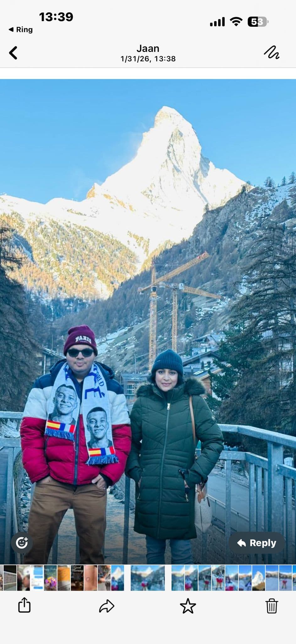 Matterhorn peak rising over Zermatt as two travelers pose on a bridge in front of the mountain, Switzerland.