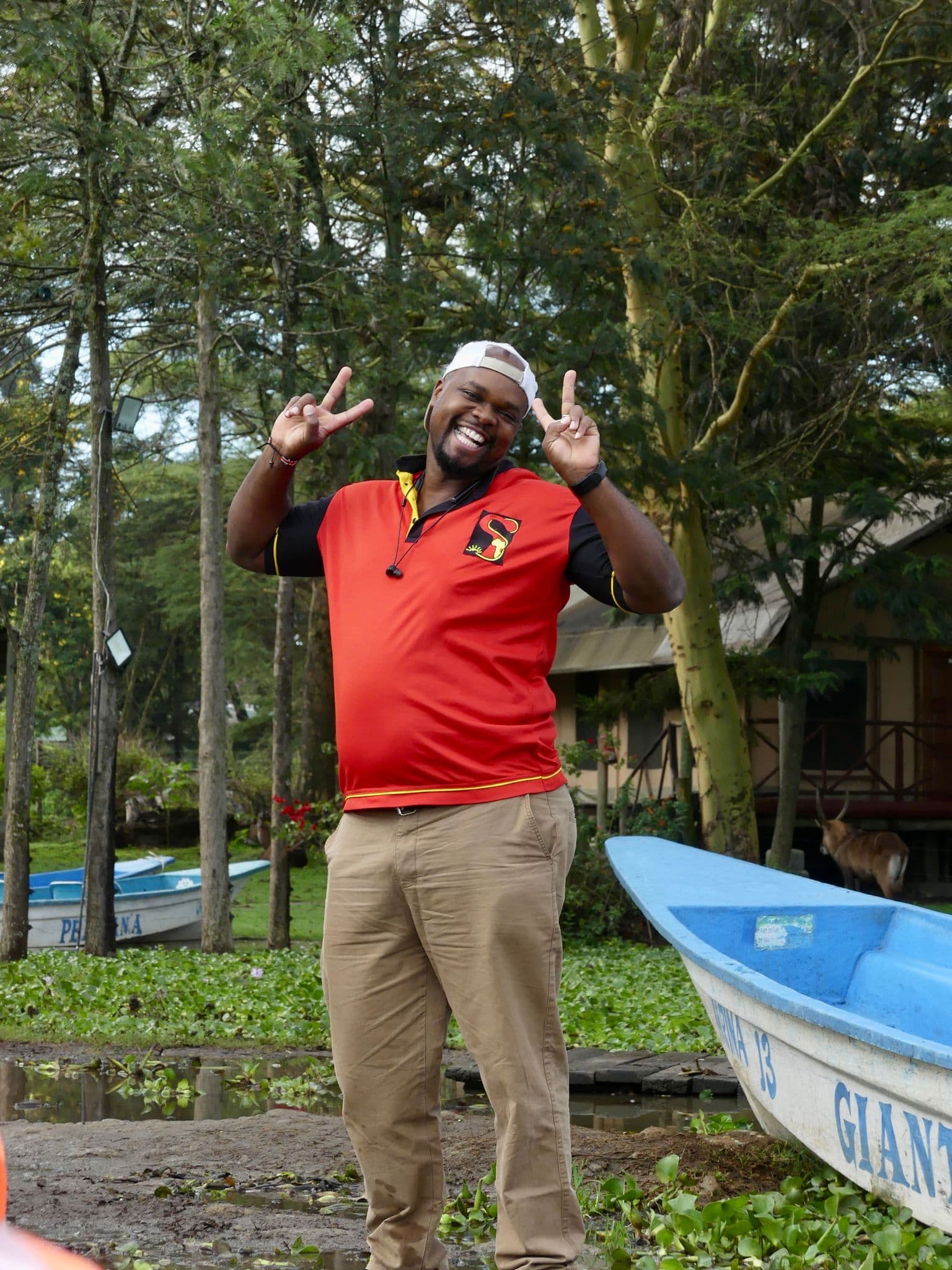Guide posing with peace signs beside boats on Lake Naivasha, Naivasha, Kenya.