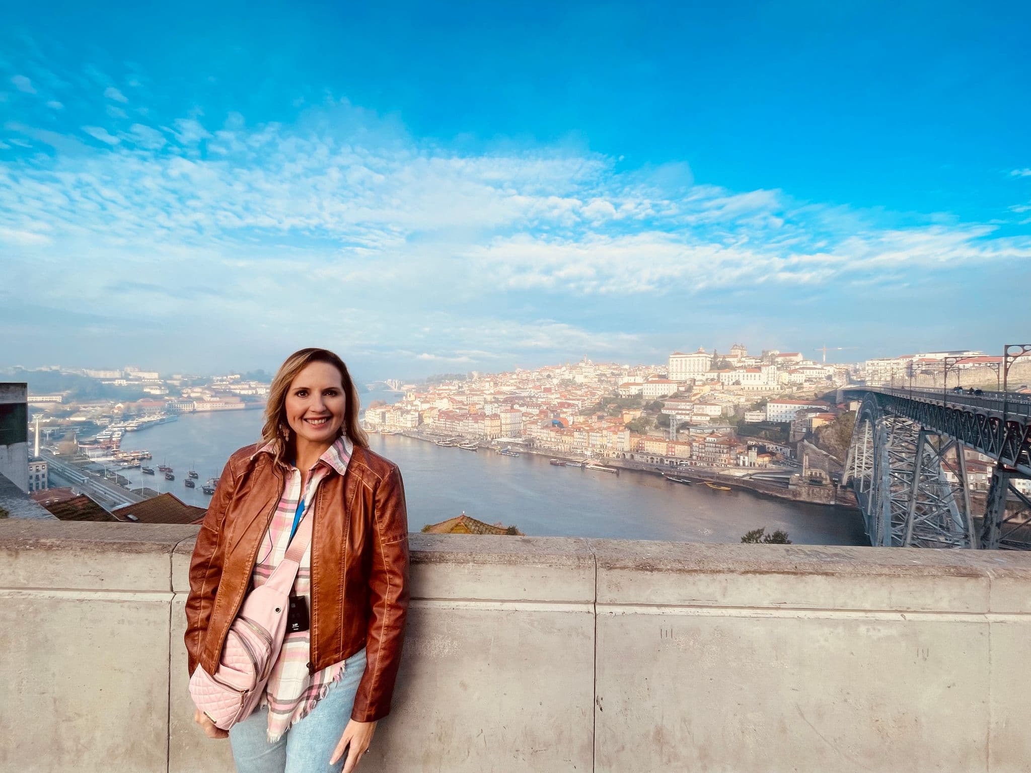 Dom Luís I Bridge and Porto riverside overlooking the Douro River with a woman leaning on a stone railing, Porto, Portugal.