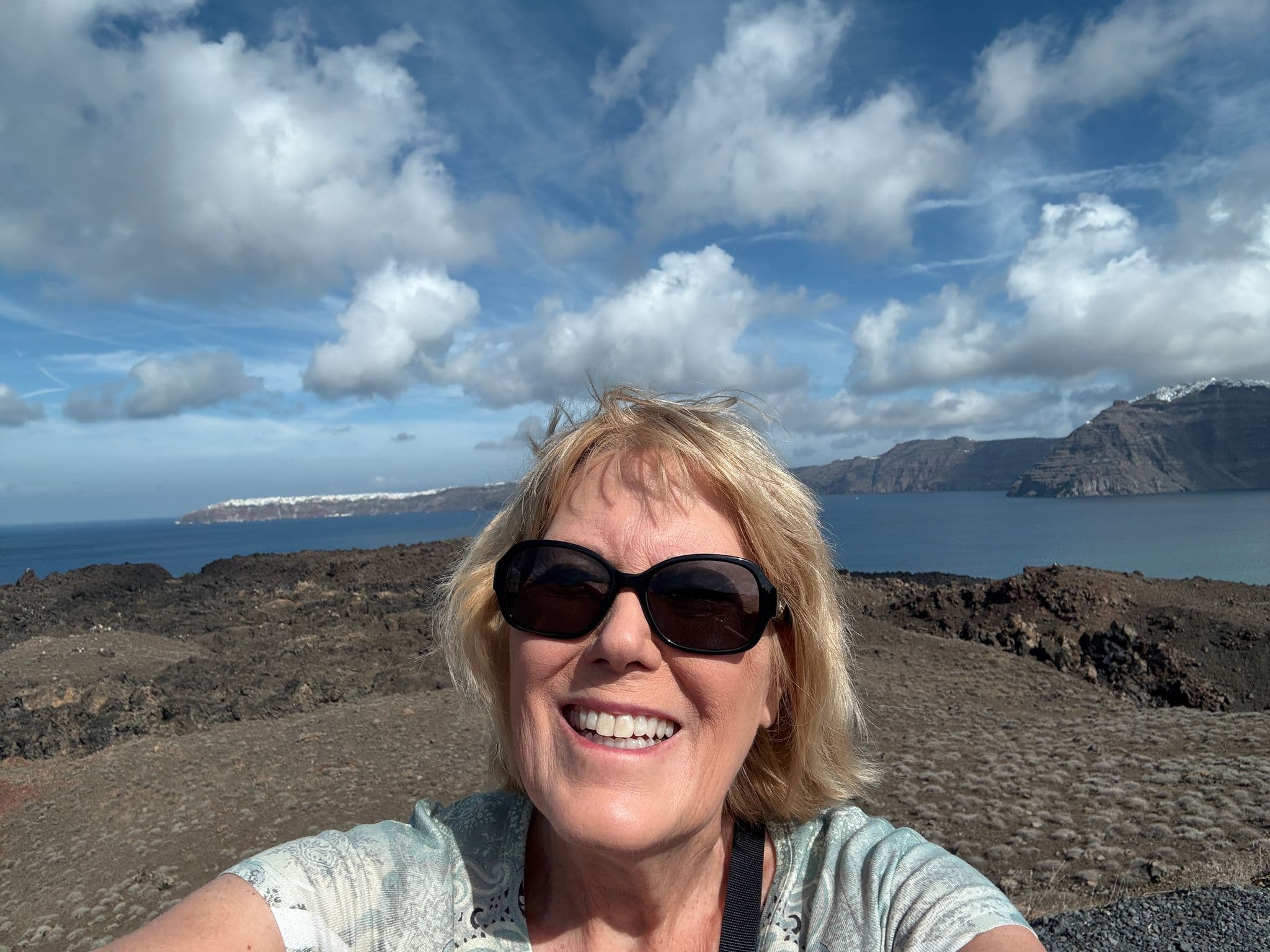 Nea Kameni volcanic caldera and sea with a traveler taking a selfie on Santorini, Greece