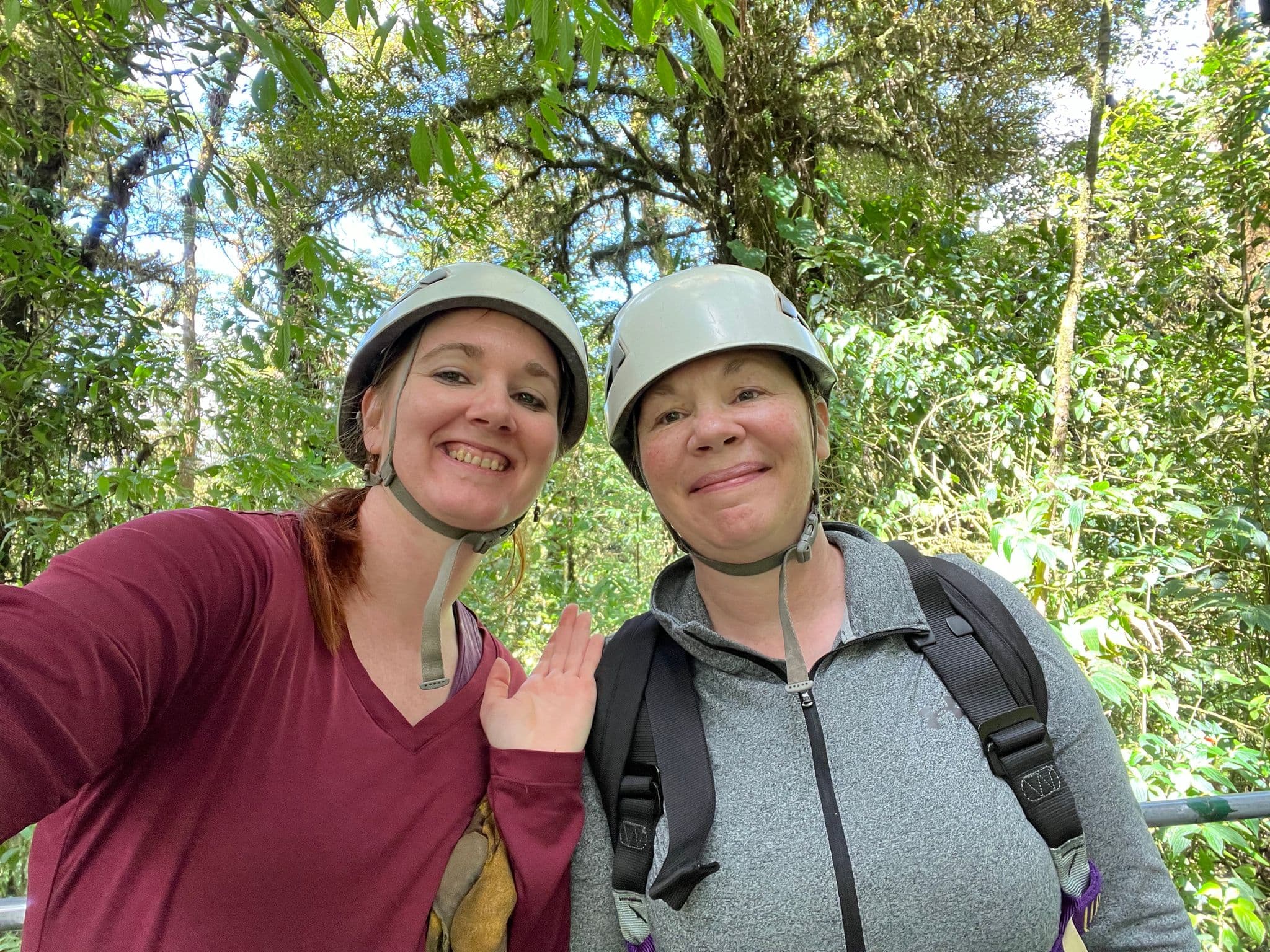 Two travelers wearing helmets posing on a zipline canopy tour in the rainforest, Costa Rica.