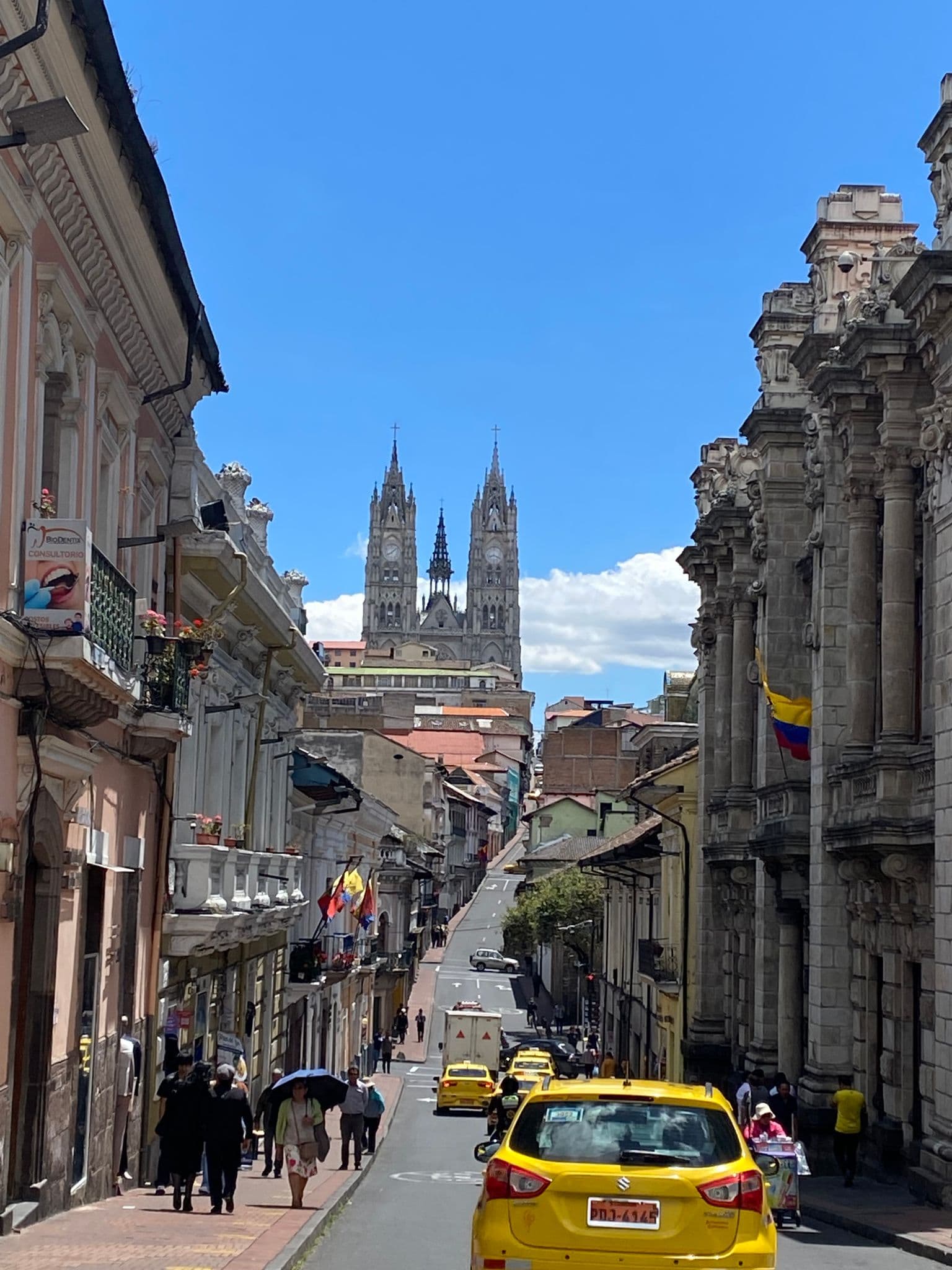 Basílica del Voto Nacional's twin spires rising above a busy Quito street with pedestrians and yellow taxis, Quito, Ecuador