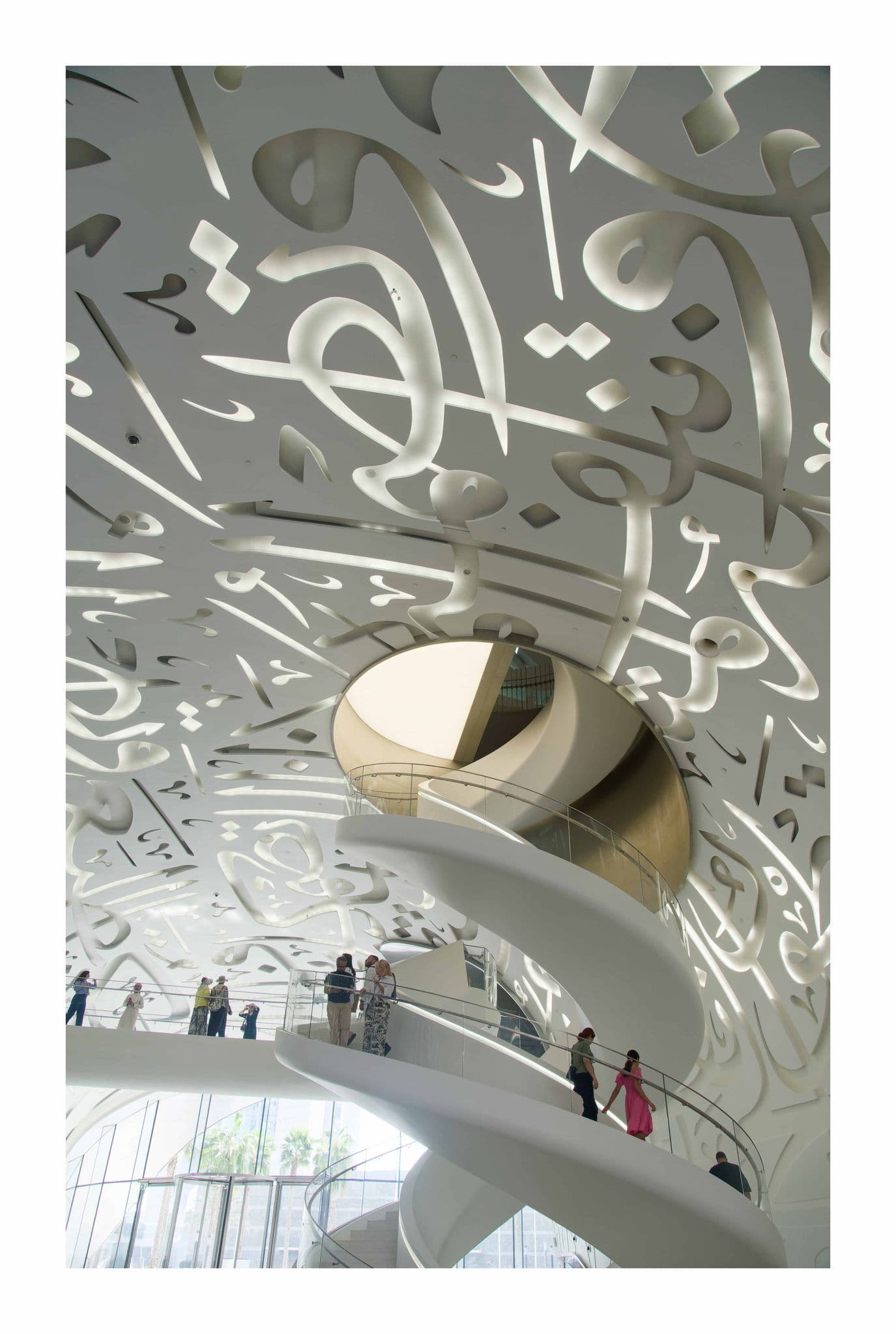 Museum of the Future interior, Dubai, UAE, showing spiral staircases and lit Arabic calligraphy ceiling with visitors.