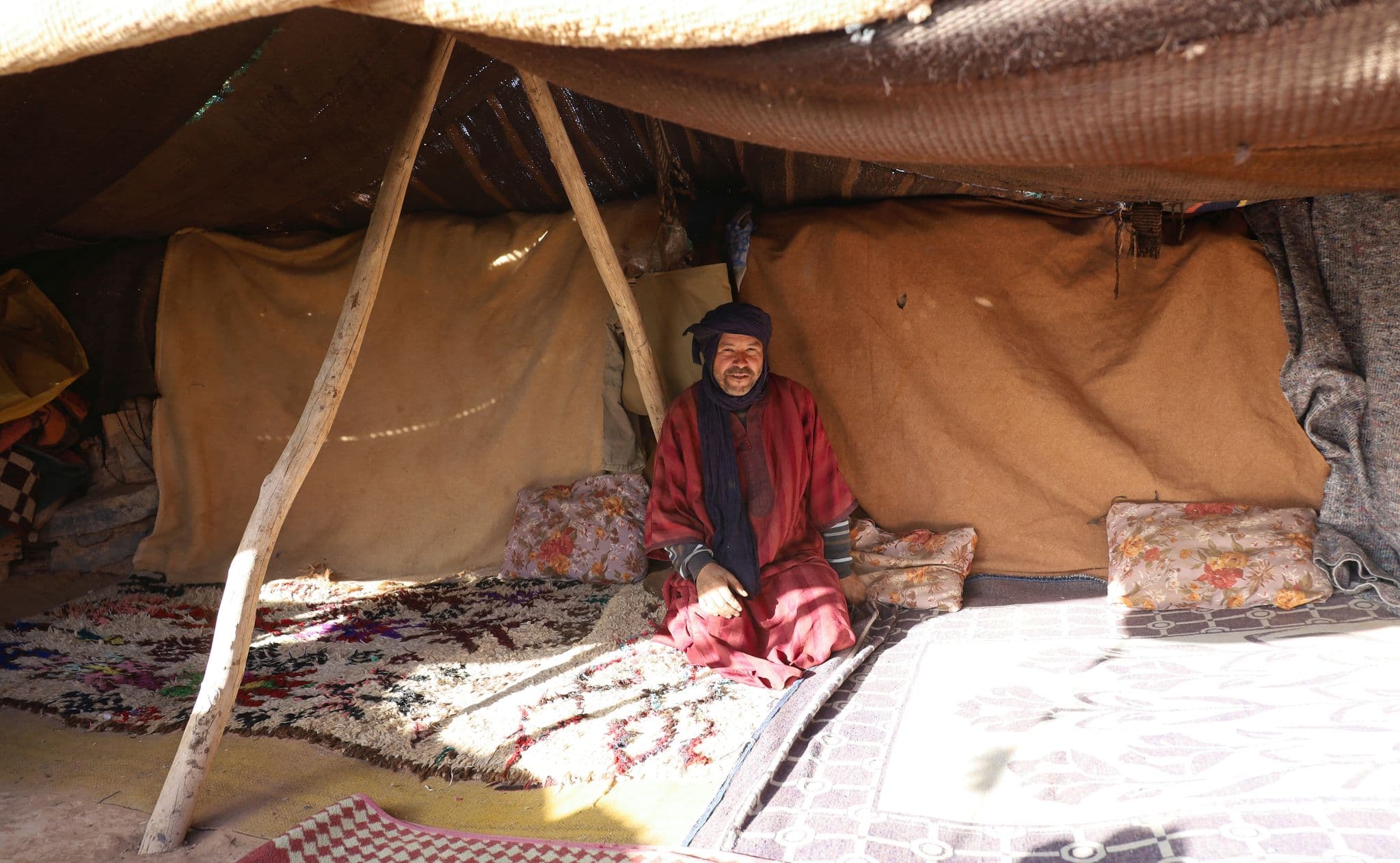 Man sitting inside a Bedouin tent on rugs and cushions, Sahara Desert, Morocco.