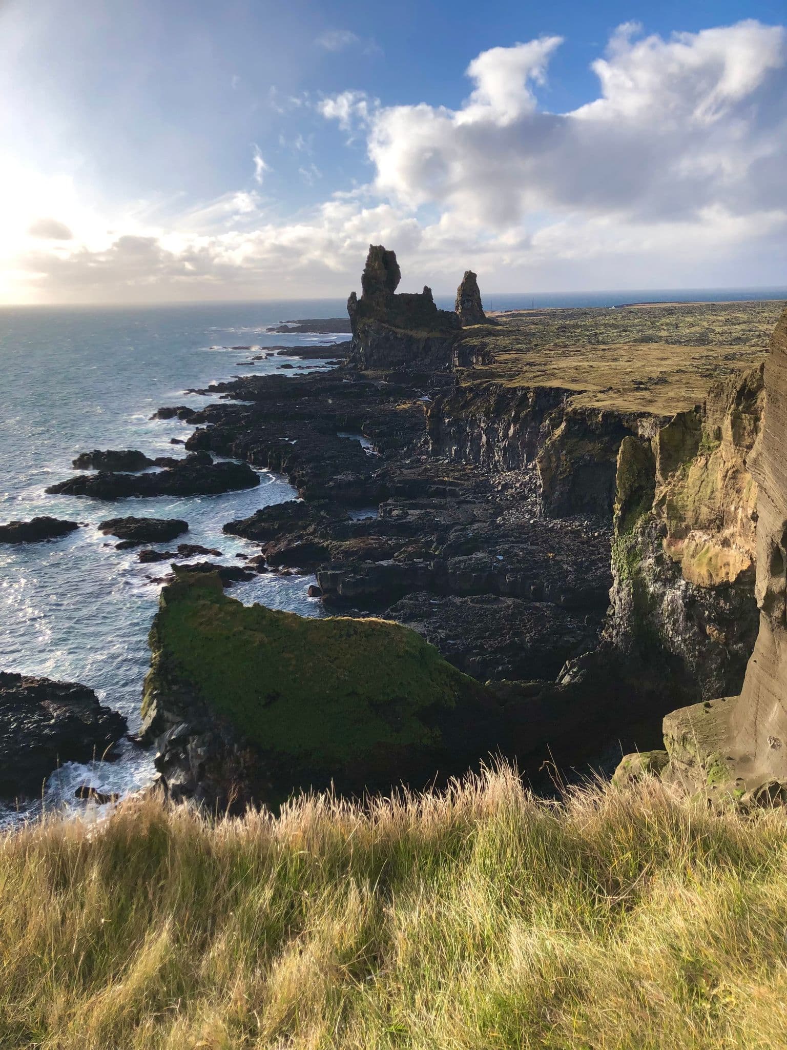 Lóndrangar sea stacks rising above a rocky shoreline on Snæfellsnes Peninsula, Iceland.