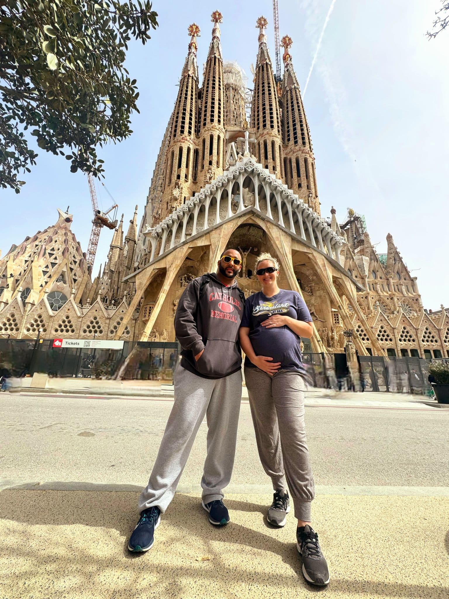 Sagrada Família in Barcelona, Spain with a couple posing in front, the woman holding her pregnant belly.