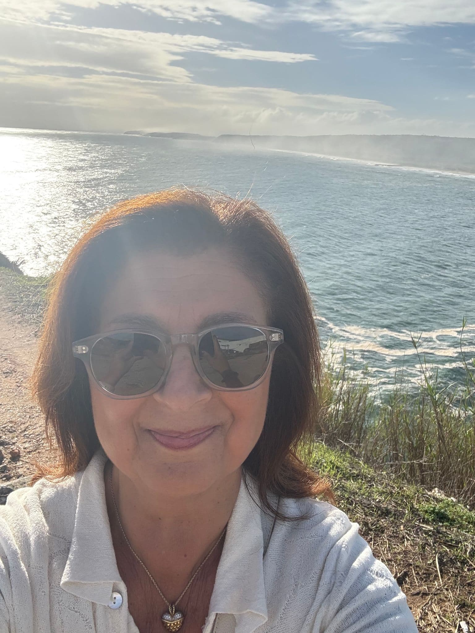 Nazaré coastline with ocean waves and a head-and-shoulders selfie of a traveler wearing sunglasses, Portugal.