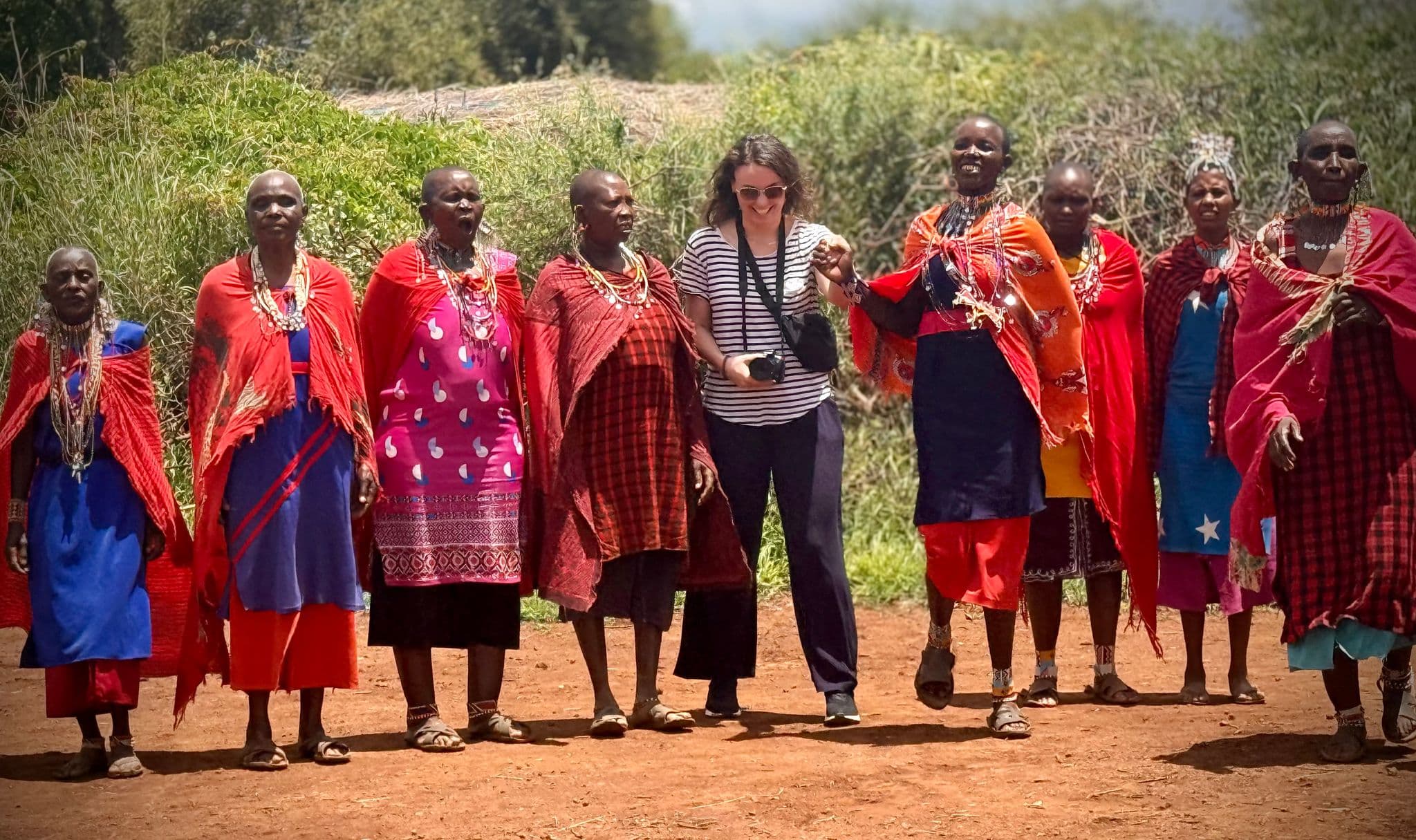Group of Maasai women standing with a traveler holding a camera in a Maasai village, Kenya