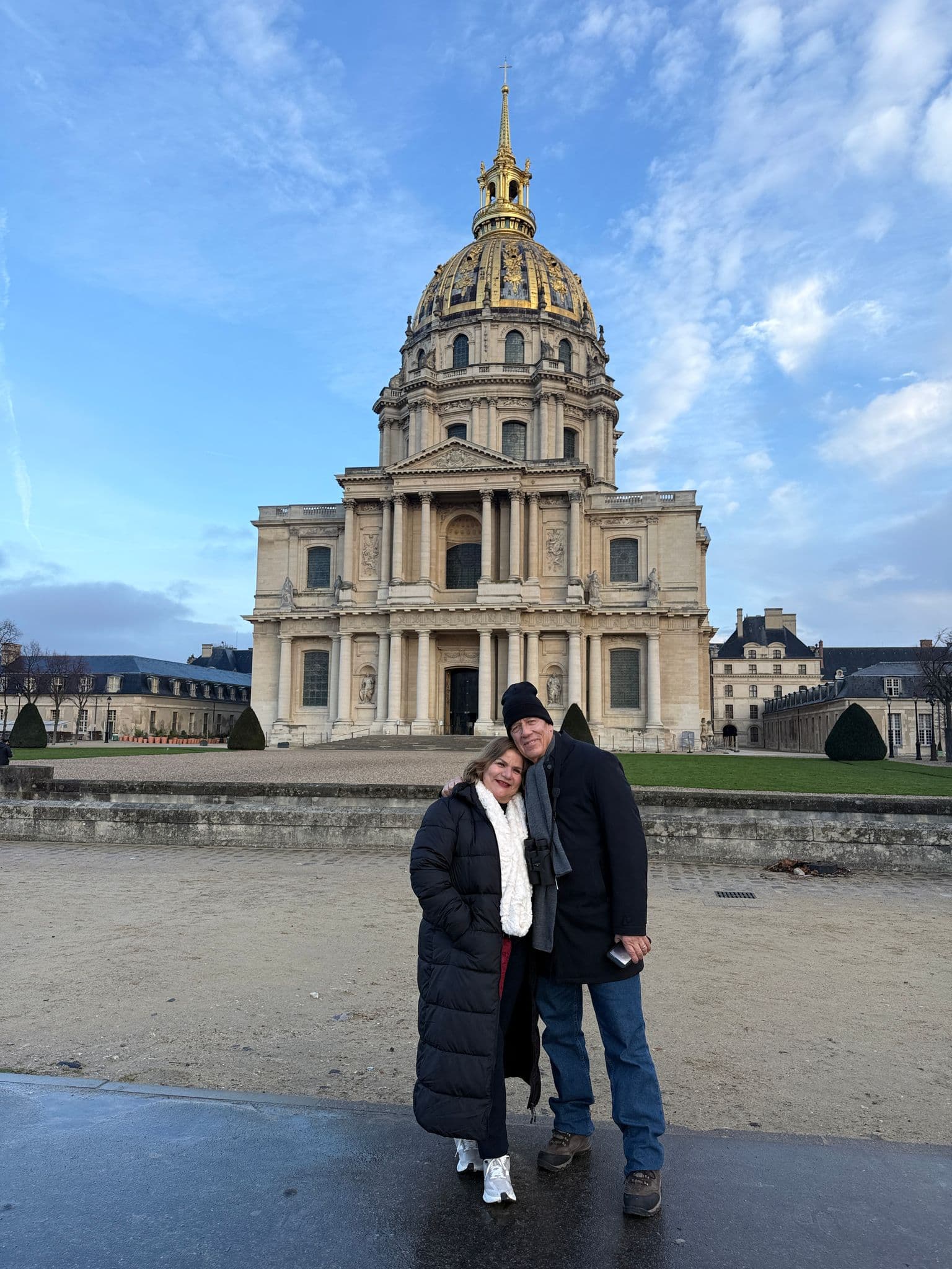 Hôtel des Invalides dome in Paris, France, with a couple standing arm-in-arm in front of the building