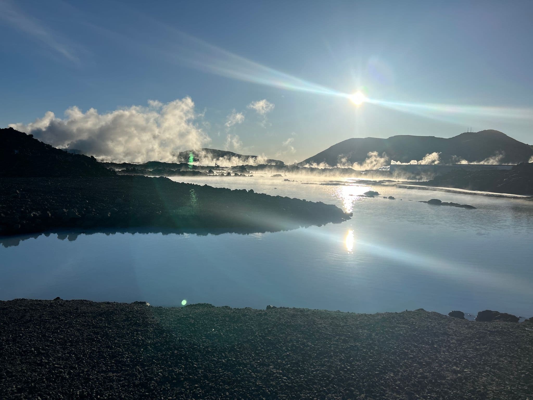 Blue Lagoon geothermal pools with steam rising and the sun reflecting on the water, Reykjanes Peninsula, Iceland.
