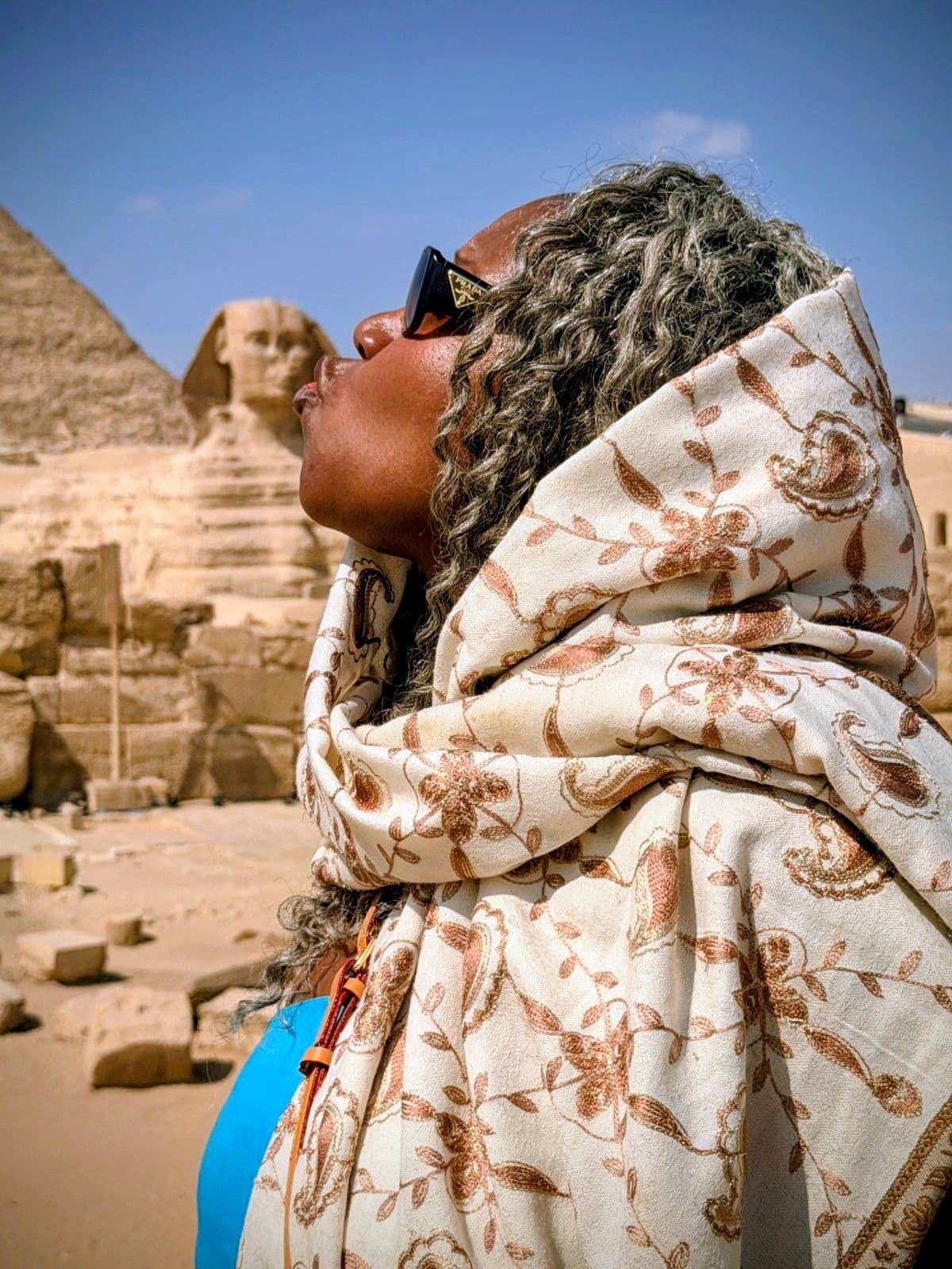 Great Sphinx of Giza seen behind a traveler wrapped in a patterned scarf at the Giza Plateau, Egypt.