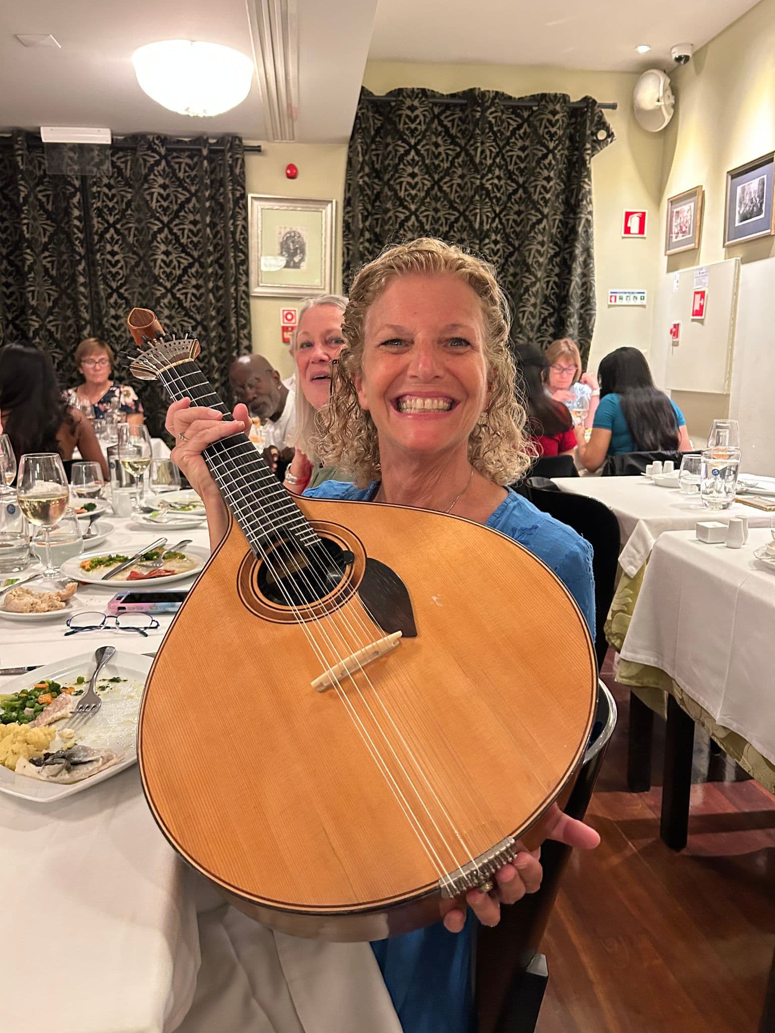 Portuguese guitar held by a smiling diner during a Fado dinner in Lisbon, Portugal.