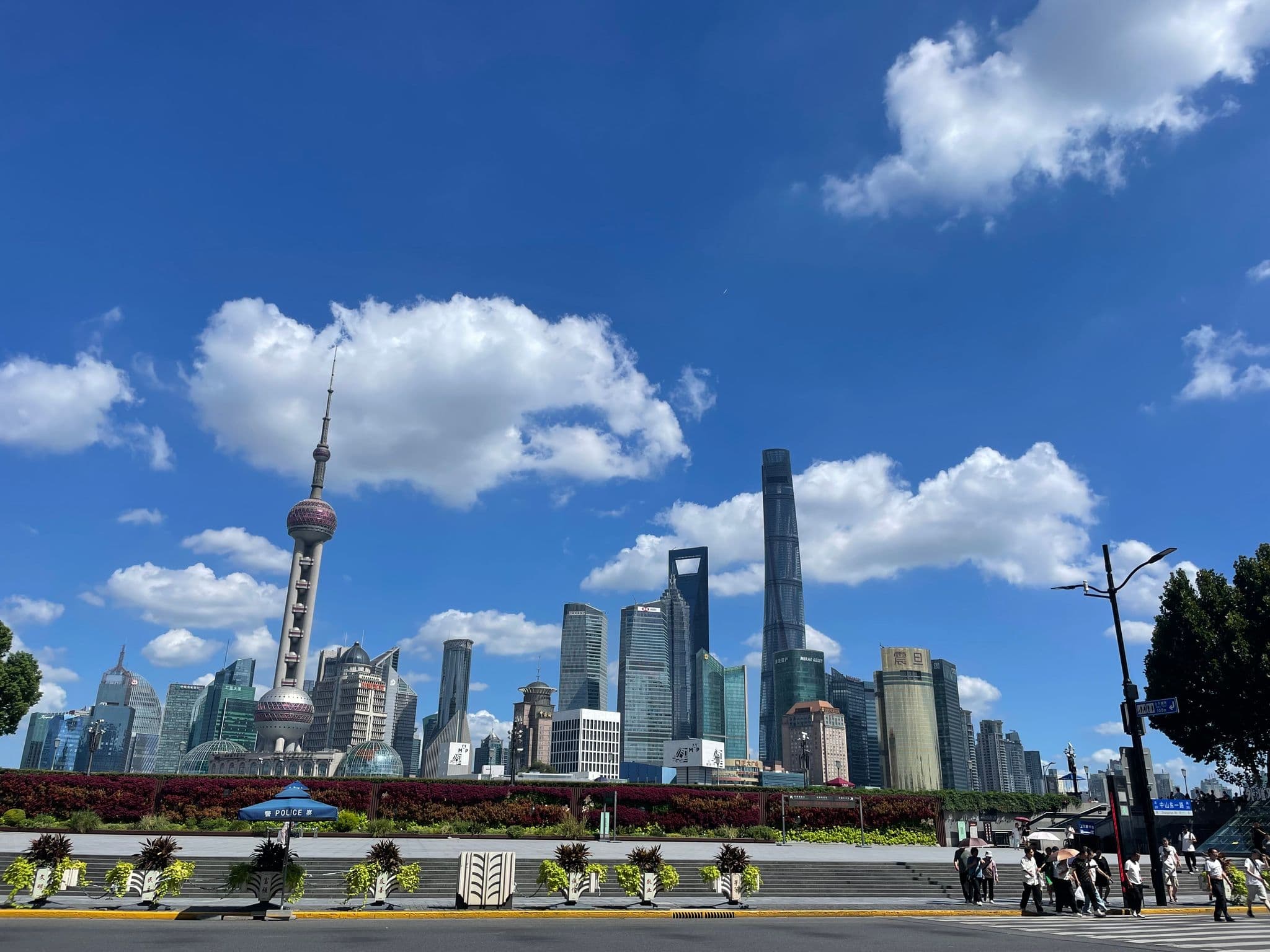 Oriental Pearl Tower and Pudong skyline with pedestrians crossing a street along the Bund, Shanghai, China.