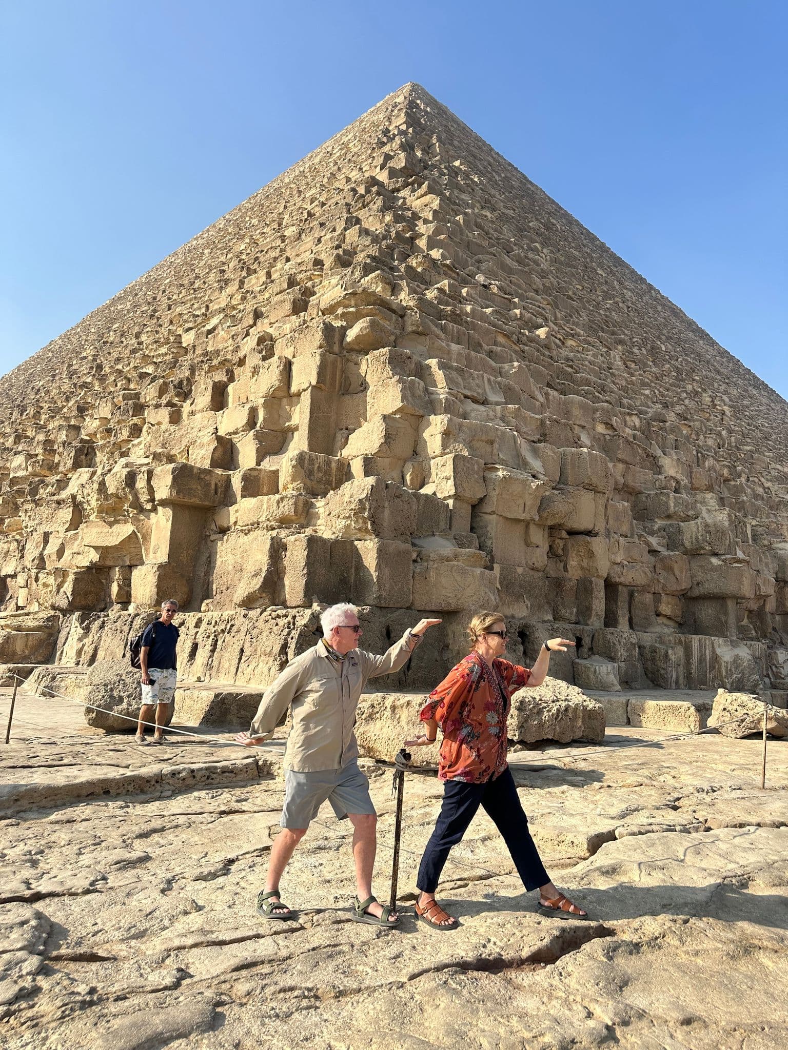 Great Pyramid of Giza with two tourists striking a playful walking pose in front, Giza, Egypt
