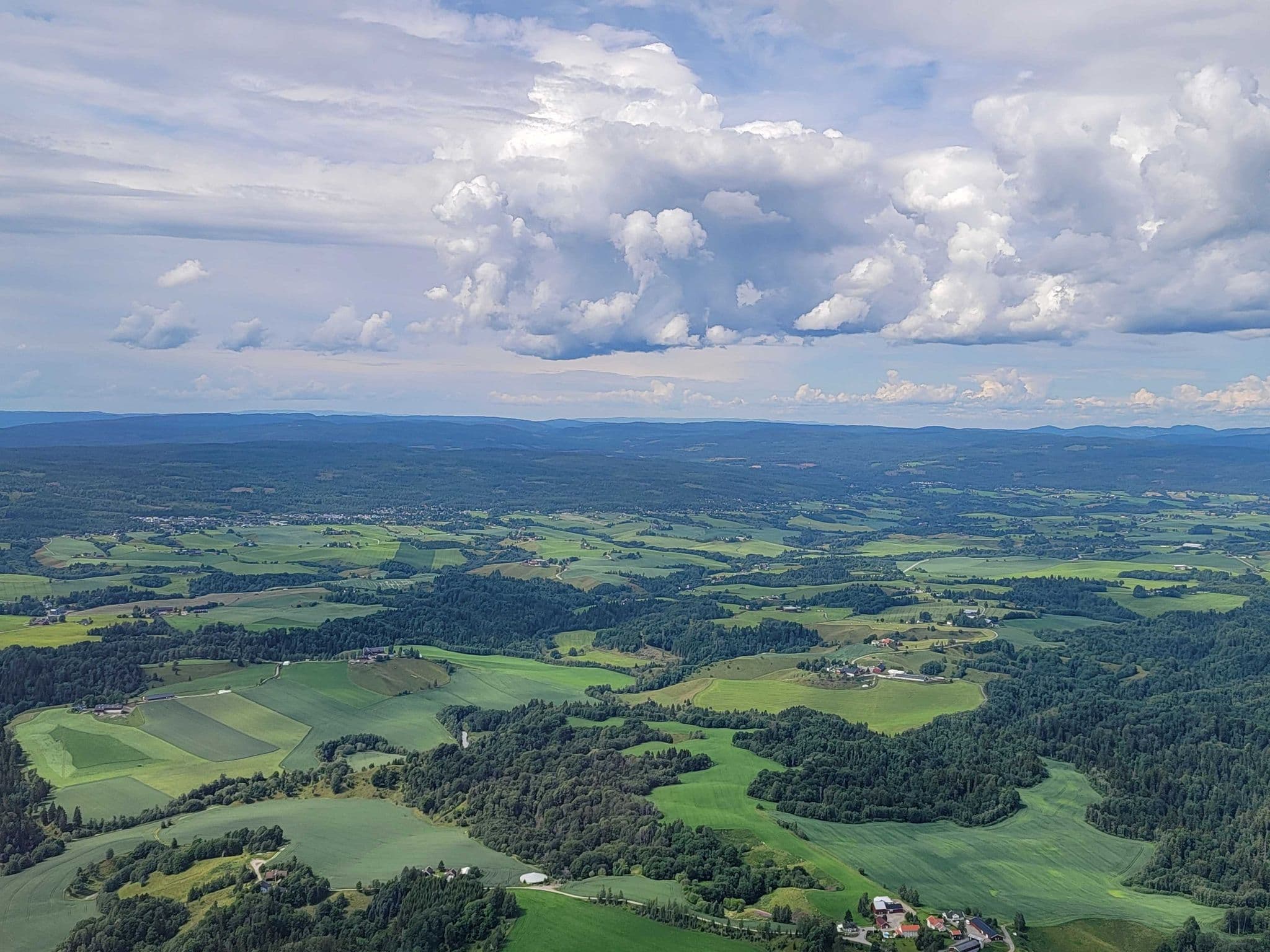Aerial view of rolling green farmland and forests outside Oslo, Norway, seen from an airplane during a return flight.