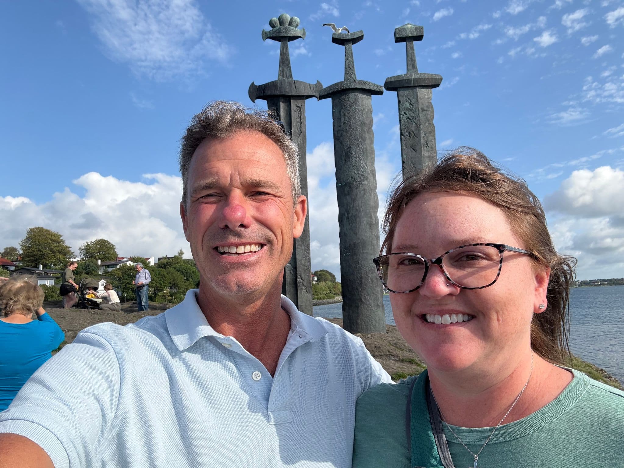 Sverd i fjell monument with three large bronze swords by the water in Stavanger, Norway, with a couple taking a selfie