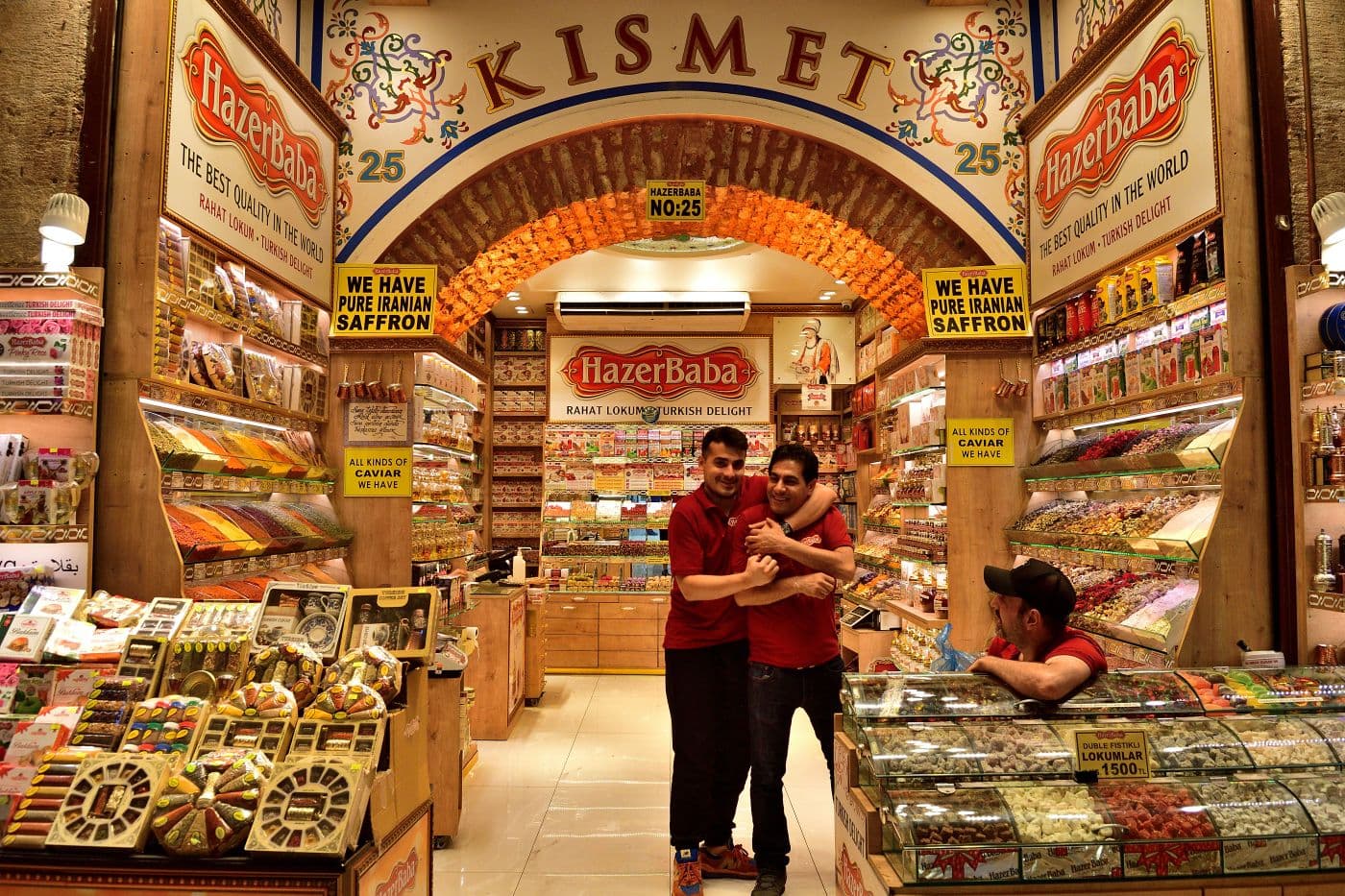 HazerBaba shop entrance in the Grand Bazaar, Istanbul with two shop workers hugging amid displays of Turkish delight and spices, Turkey