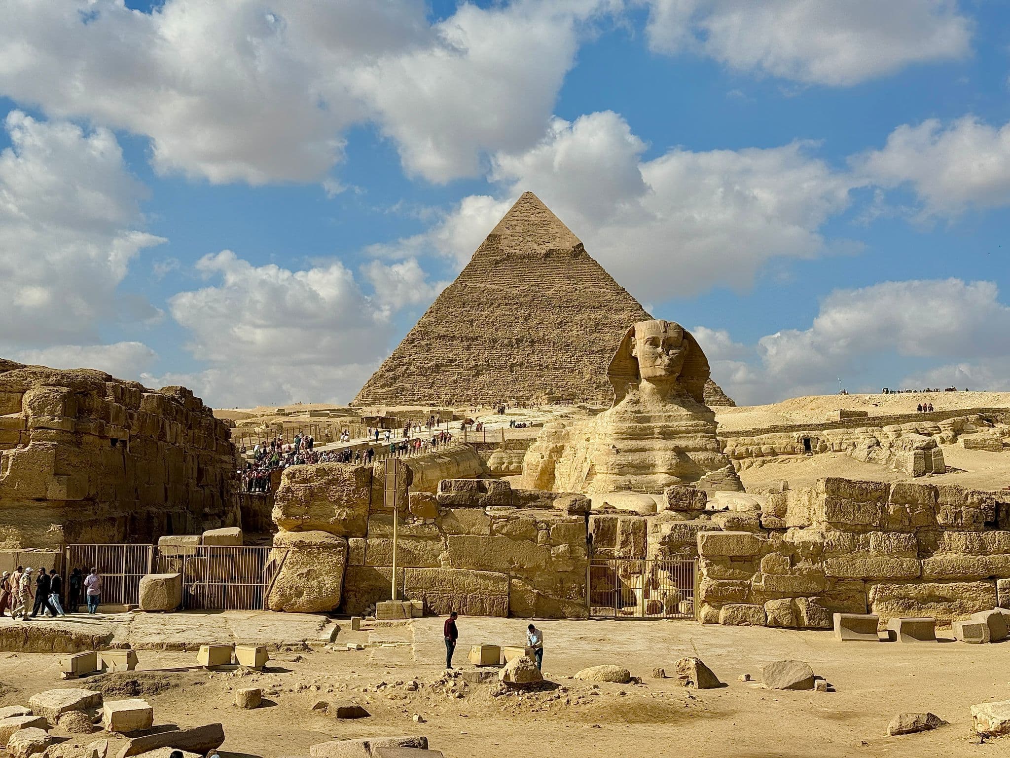 Great Sphinx of Giza reclining before the Pyramid of Khafre with tourists walking around, Giza, Egypt