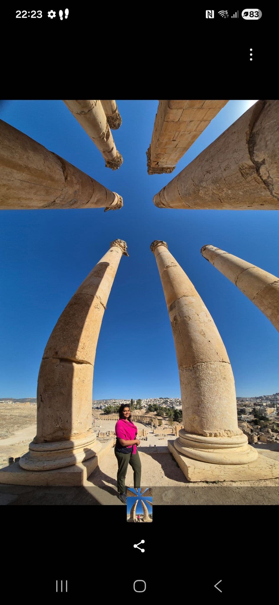 Ancient Temple of Artemis columns framing a traveler standing between them with Jerash ruins in the background, Jordan.