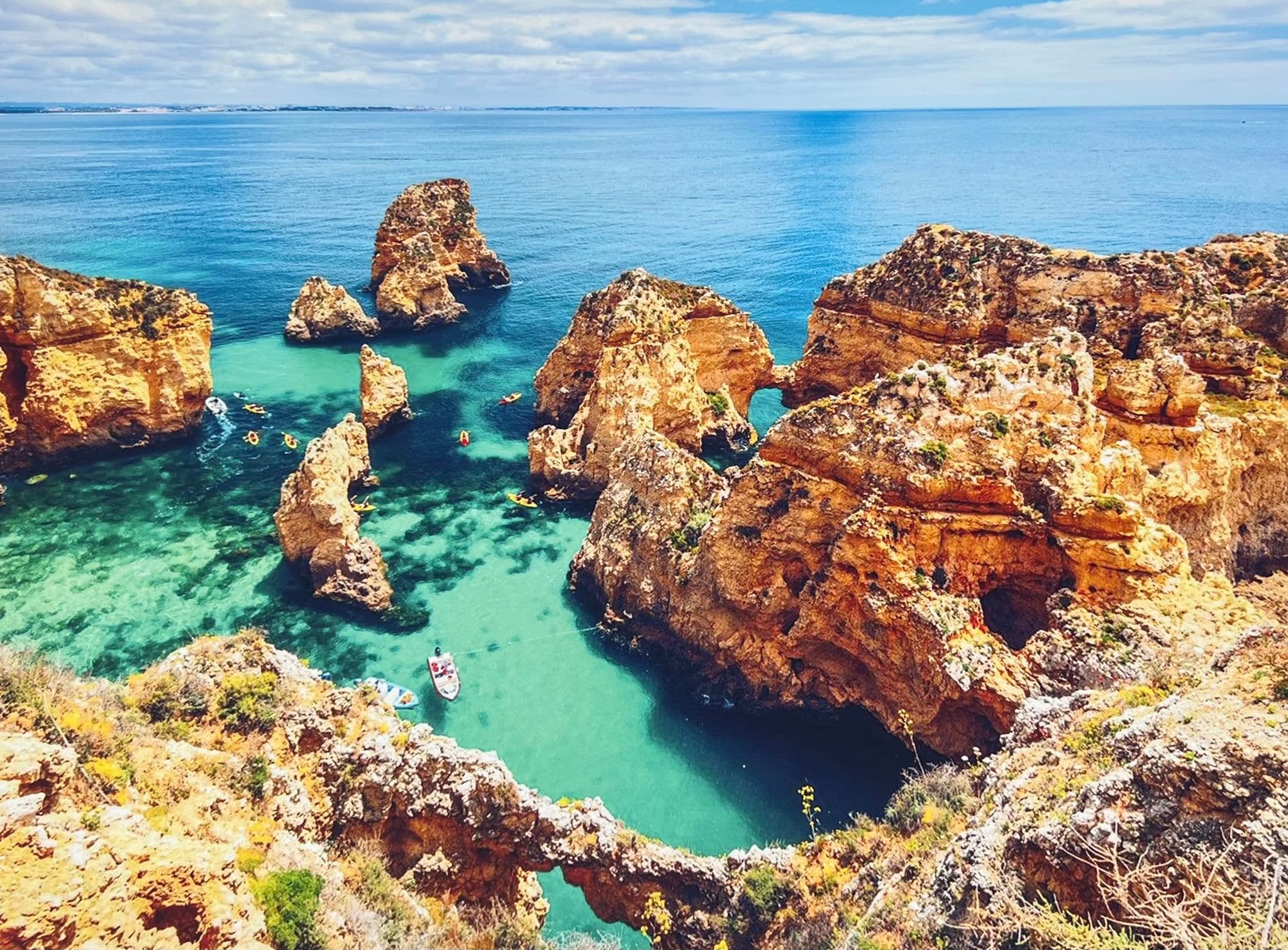Ponta da Piedade cliffs with boats and kayaks in turquoise water, Lagos, Algarve, Portugal.