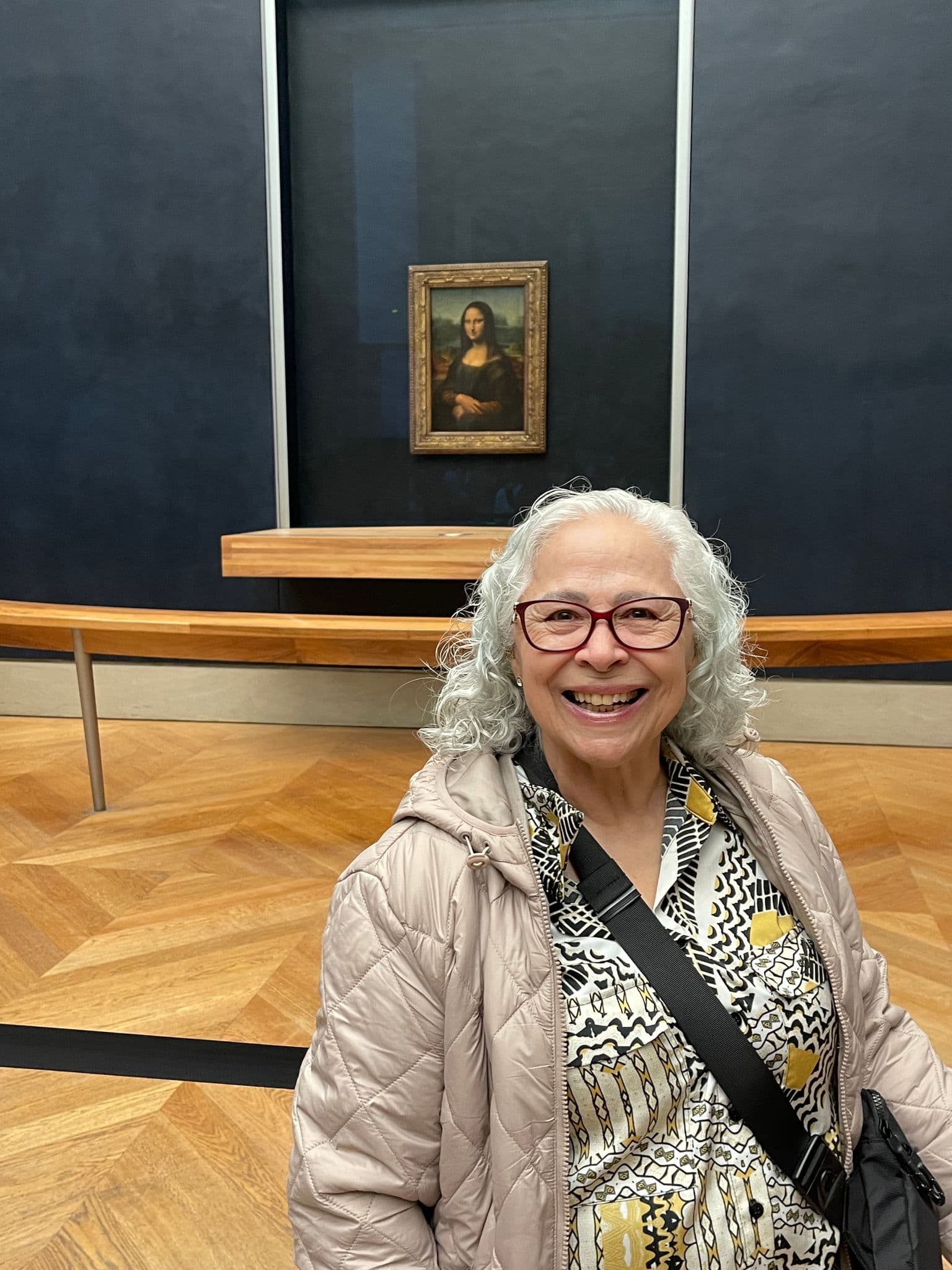 Mona Lisa on display with a smiling museum visitor posing in the foreground at the Louvre, Paris, France.
