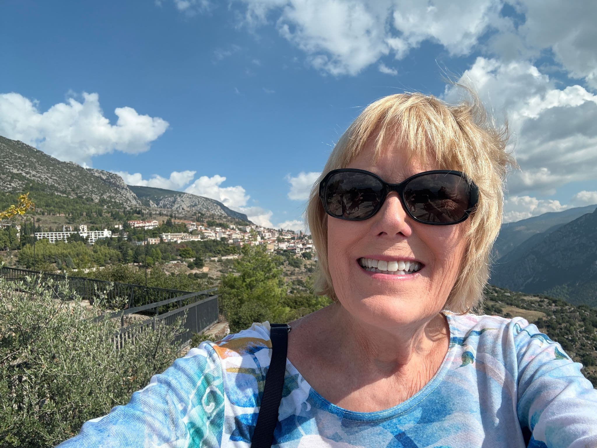 Woman taking a selfie with a mountainside village and valley between Kalambaka and Delphi, Greece.