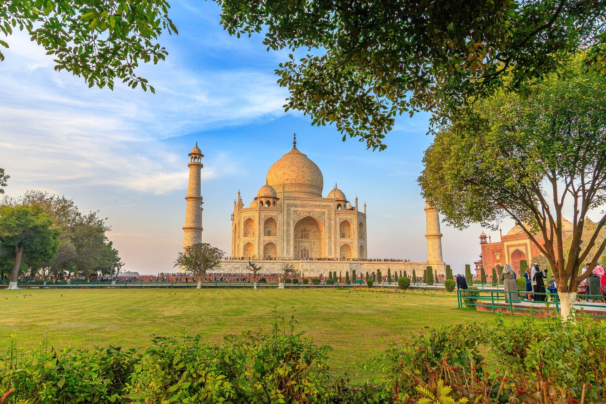 Taj Mahal framed by the Charbagh gardens with visitors on the forecourt in Agra, India
