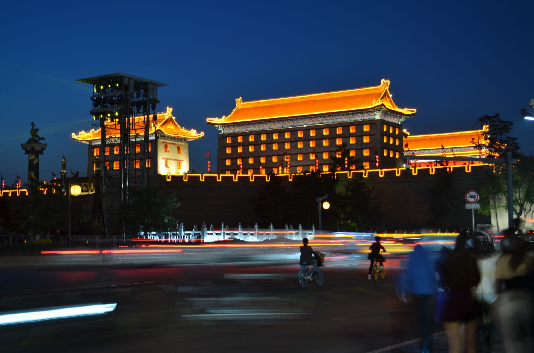 Xi'an City Wall (South Gate) lit at night with cyclists and streaking car lights in Xi'an, China.