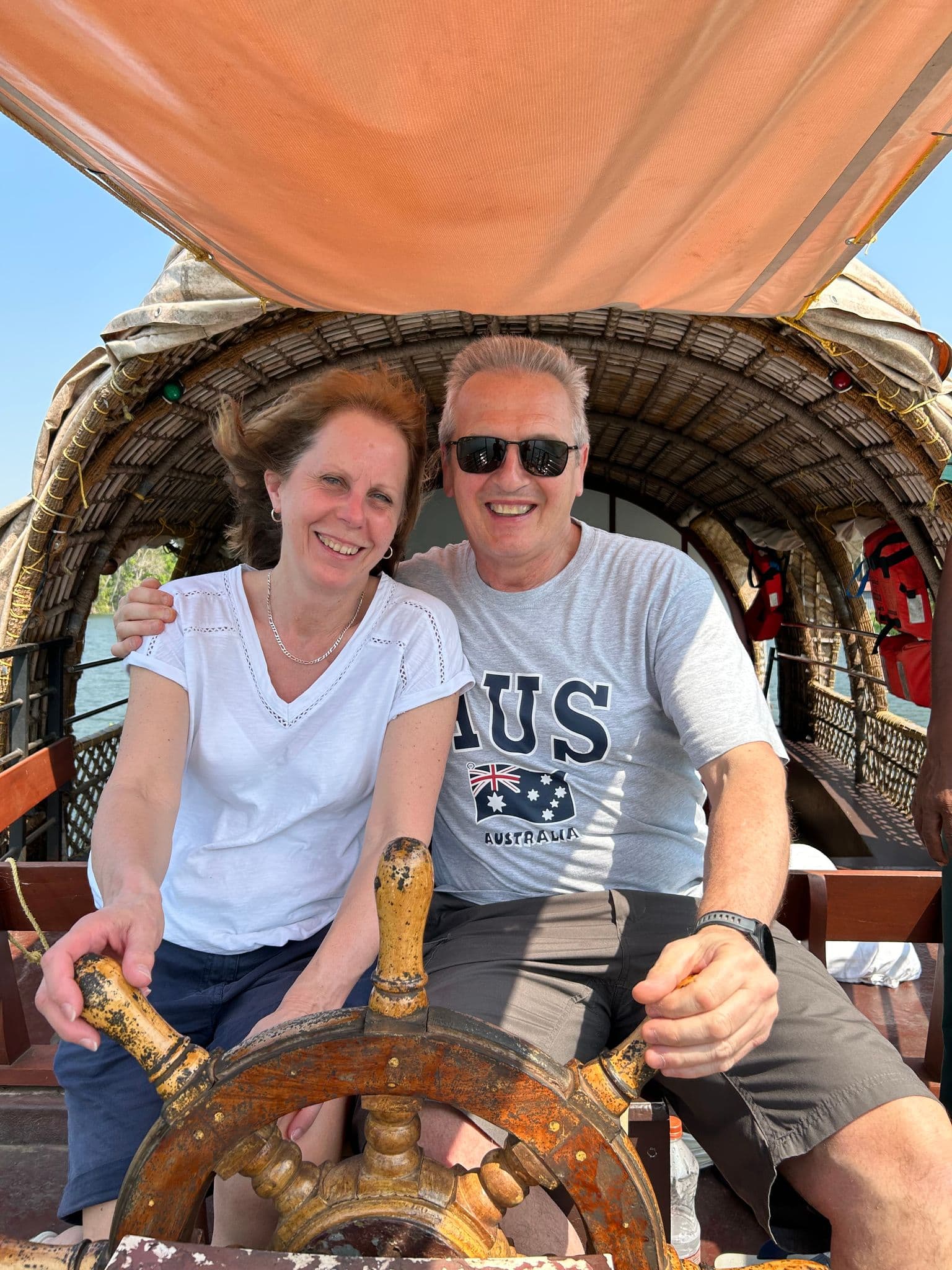 Couple steering a traditional houseboat on the Alleppey (Alappuzha) backwaters in Kerala, India.