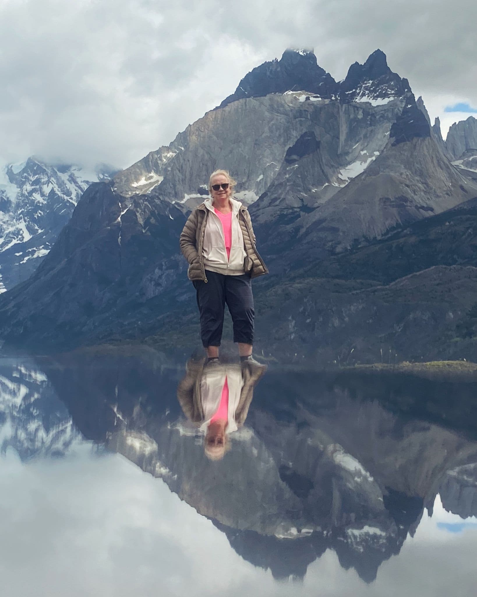 Torres del Paine mountains with a traveler standing and reflected in a calm lake, Torres del Paine National Park, Chile