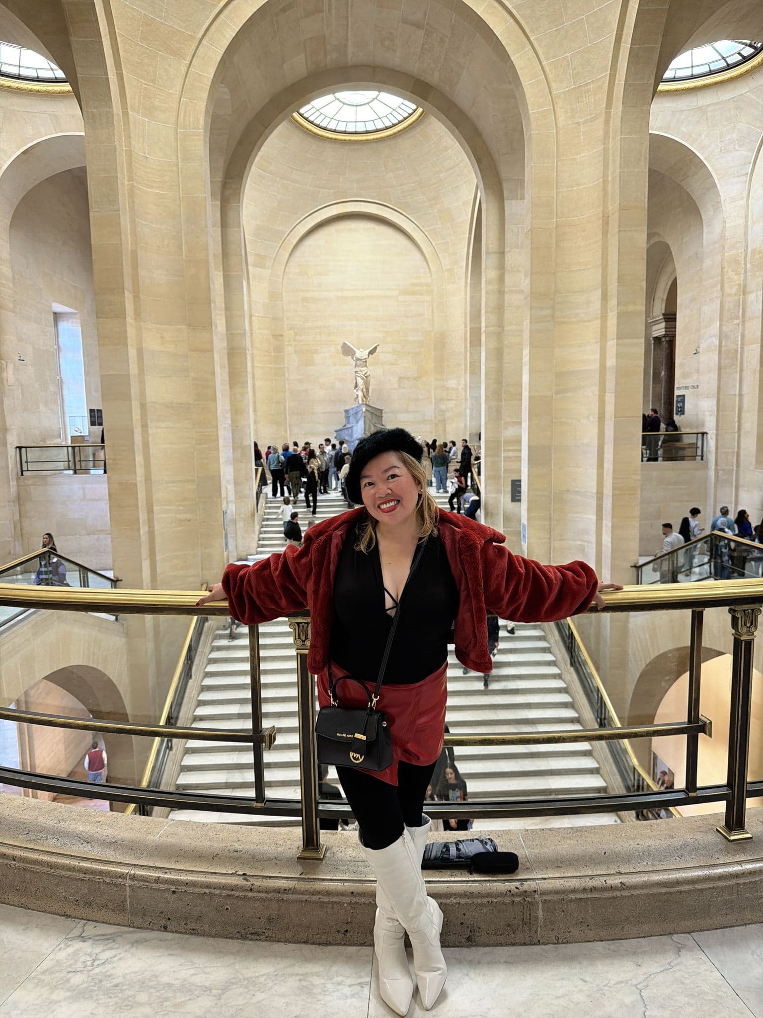 Winged Victory of Samothrace on the Daru staircase at the Louvre Museum with a traveler leaning on the railing, Paris, France.
