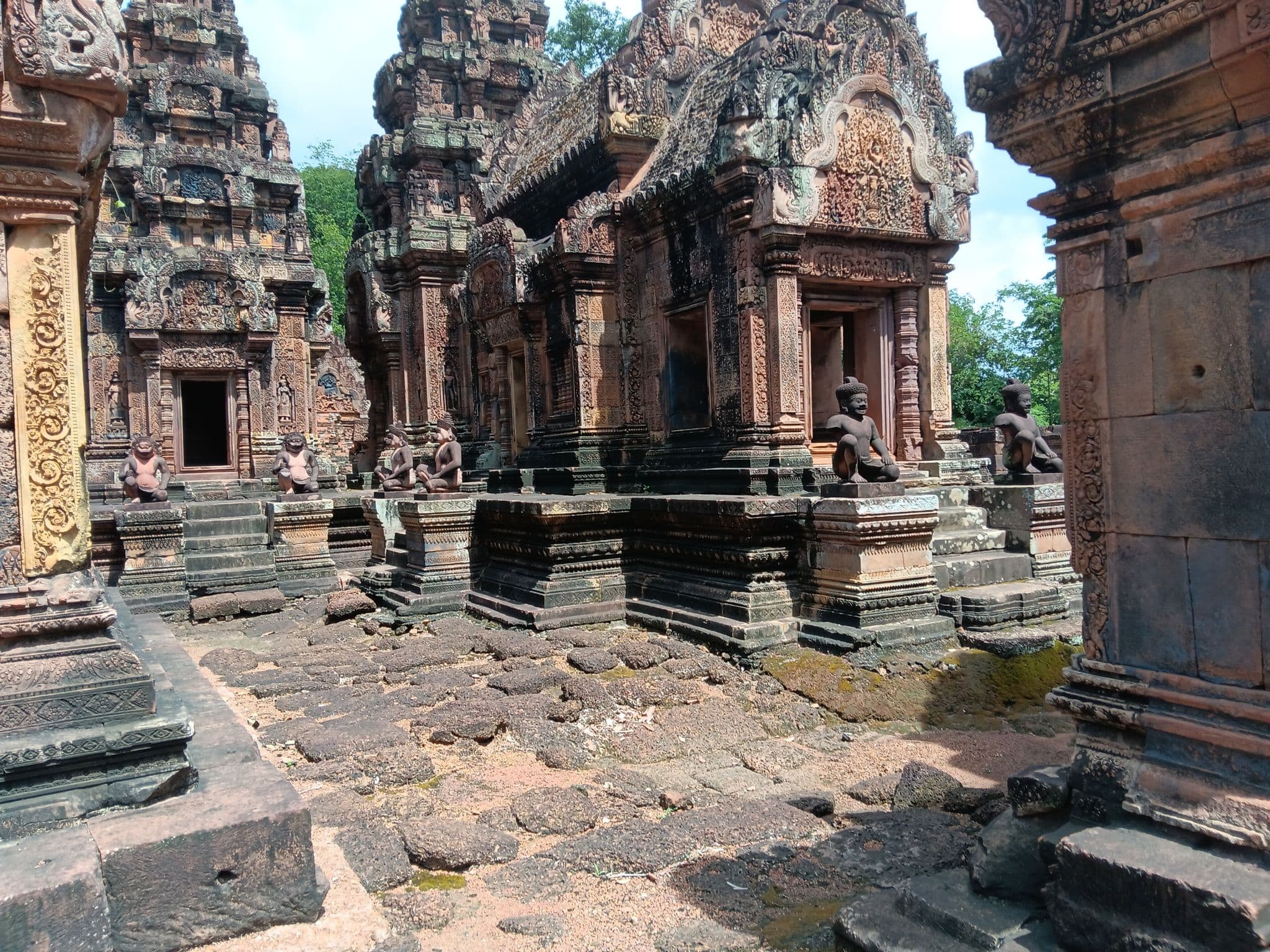 Banteay Srei temple's ornately carved sandstone shrines with seated guardian statues in Siem Reap, Cambodia.