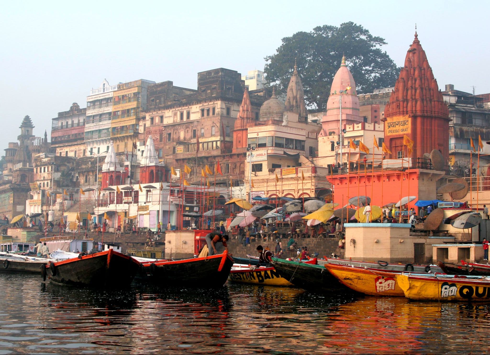 Varanasi ghats at Prayag Ghat with boats on the Ganges and people on the stone steps in Varanasi, India.