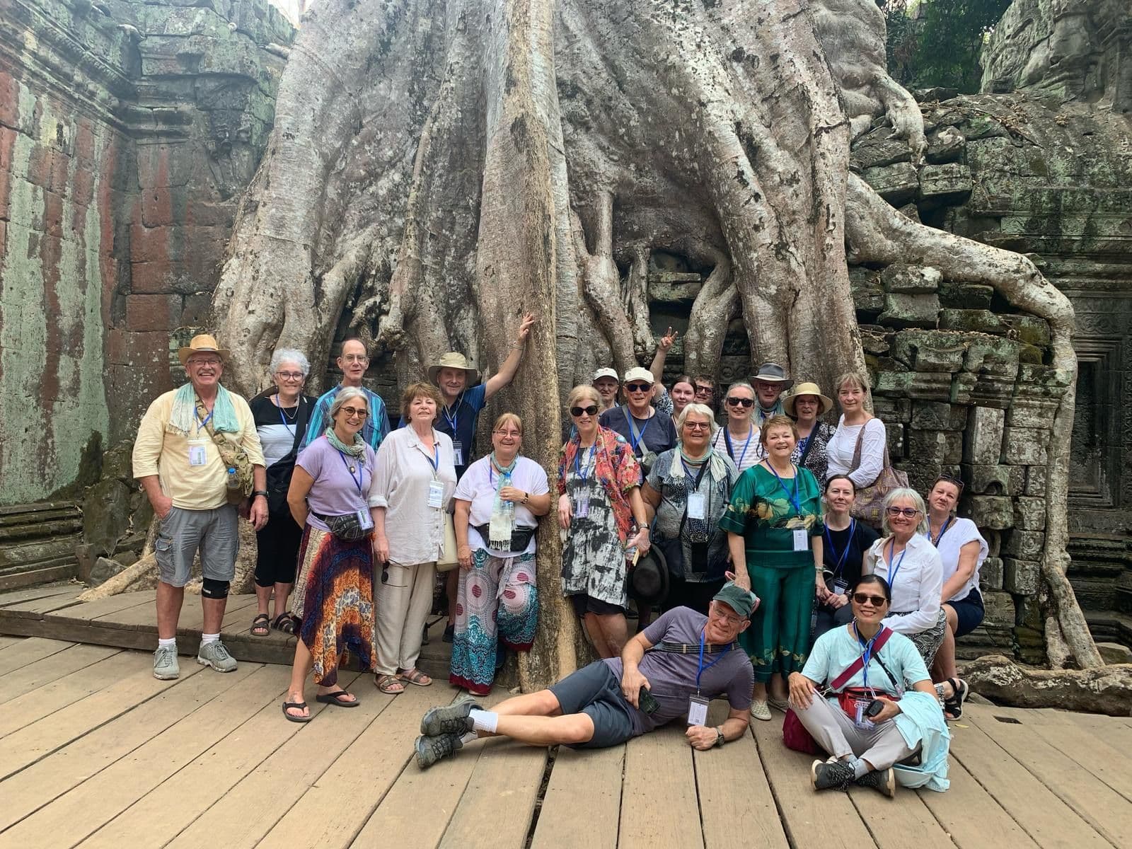 Large tree roots at Ta Prohm temple with a tour group posing in front, Angkor, Siem Reap, Cambodia.