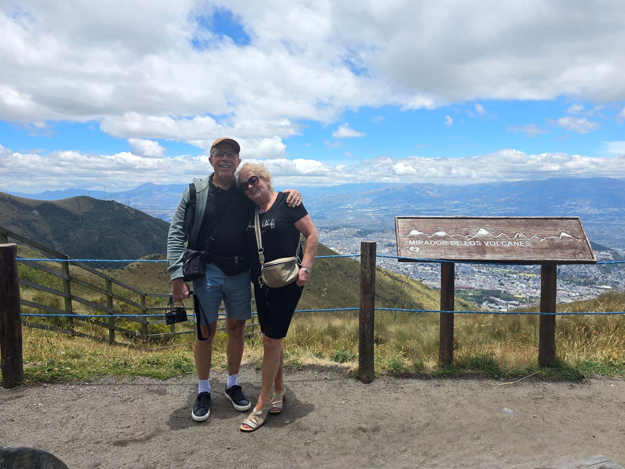 Mirador de los Volcanes viewpoint with a couple posing at the overlook, Quito and the Andes in the background, Ecuador.