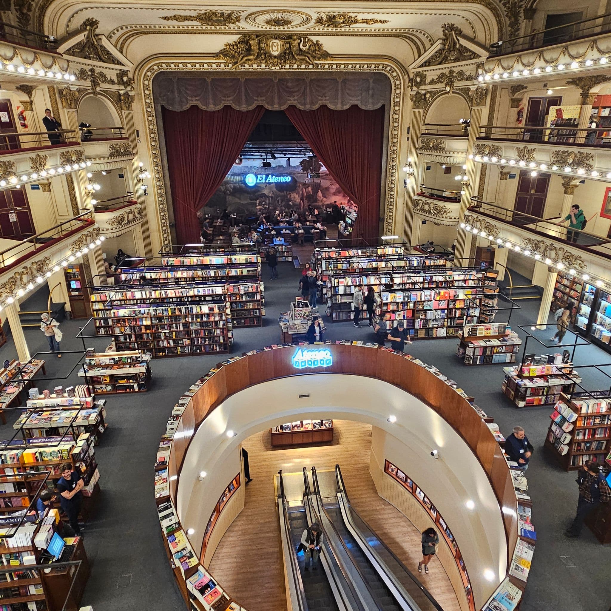 El Ateneo Grand Splendid bookstore interior showing rows of bookshelves and visitors browsing beneath the ornate theater stage in Buenos Aires, Argentina.