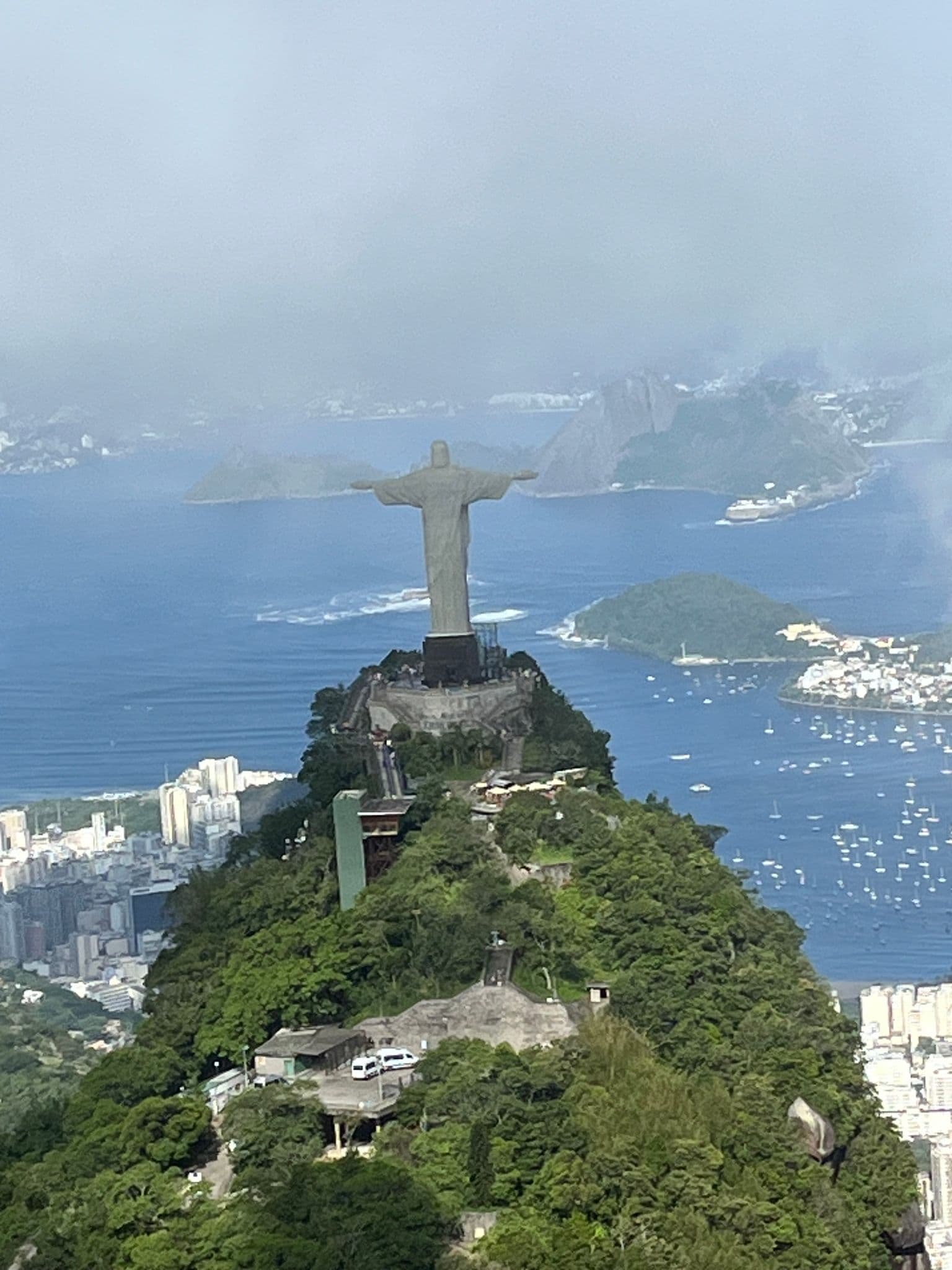Christ the Redeemer statue on Corcovado Hill seen from a helicopter over Rio de Janeiro, Brazil, with Guanabara Bay and Sugarloaf Mountain visible