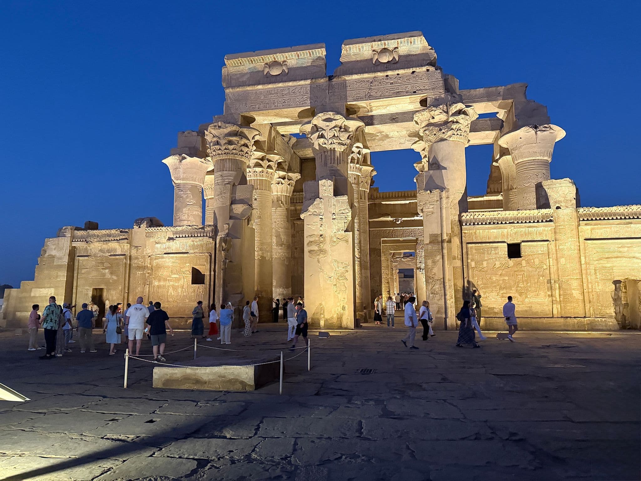Kom Ombo Temple illuminated at night with visitors walking and taking photos in the courtyard, Kom Ombo (Aswan), Egypt.