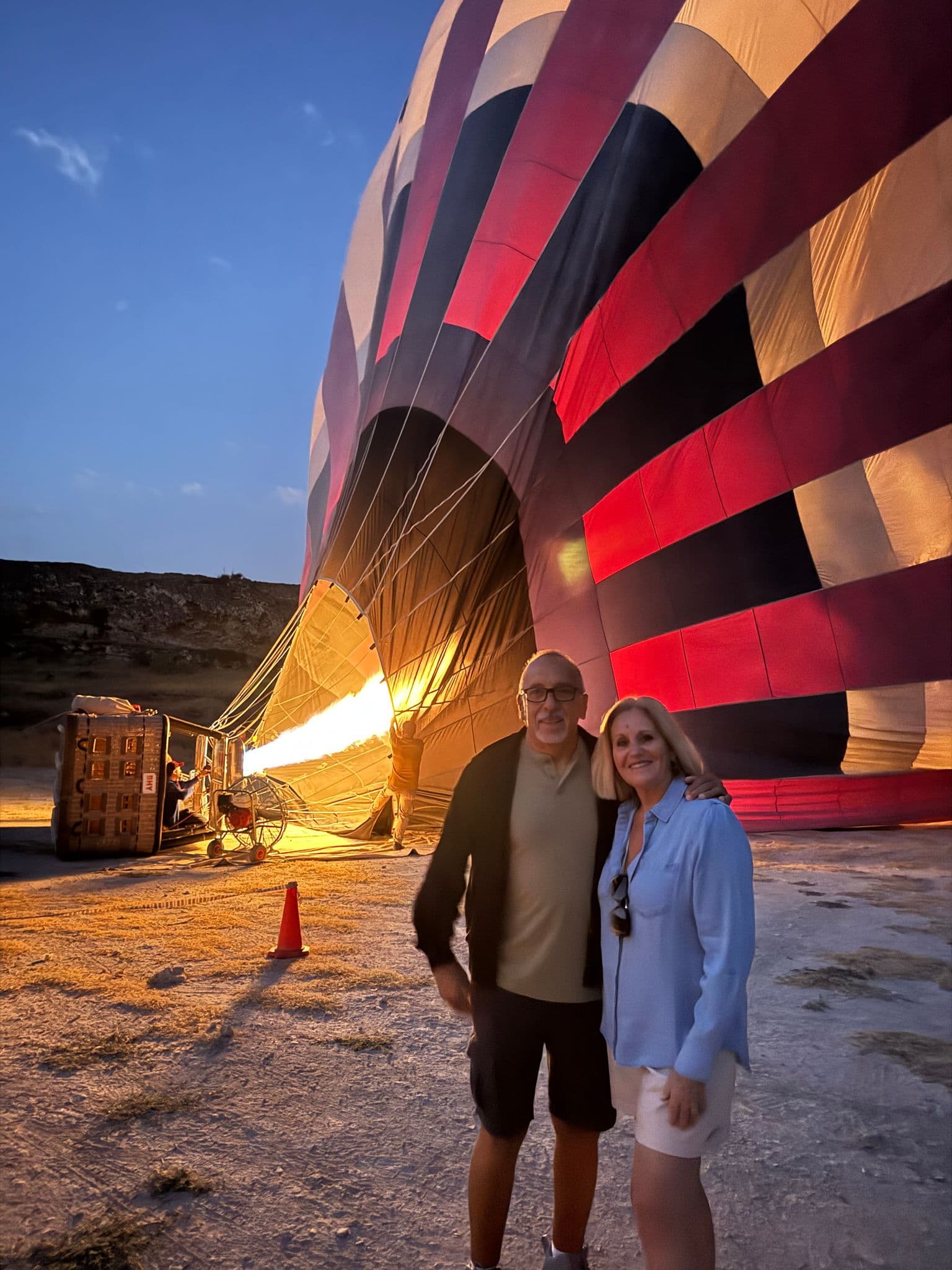 Hot air balloon being inflated with burners while a couple poses in front in Cappadocia, Turkey.