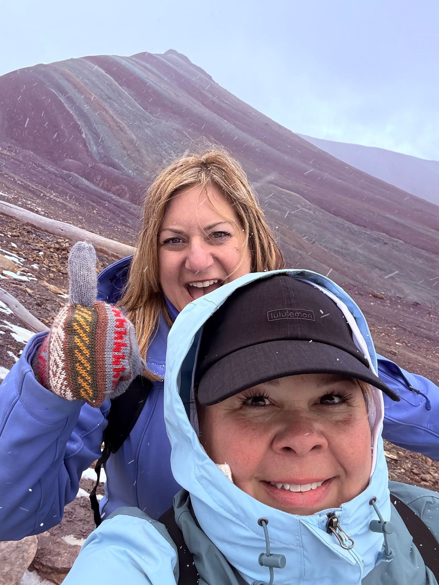 Vinicunca (Rainbow Mountain) with two women taking a snowy selfie near Cusco, Peru.