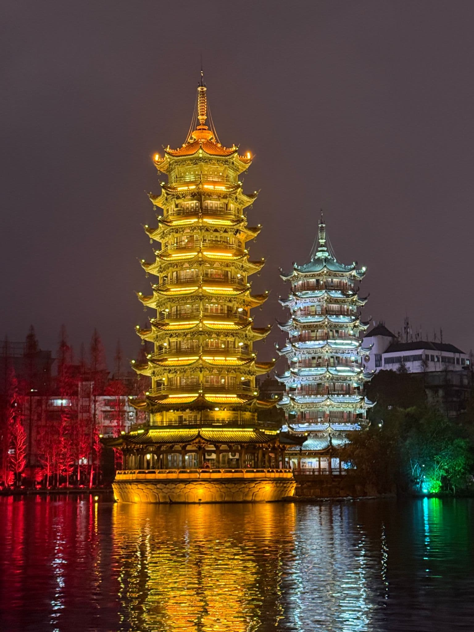 Sun and Moon Pagodas (Riyue Shuangta) lit at night, reflecting on the water in Guilin, China.