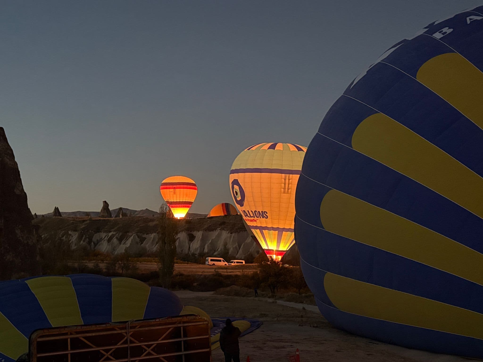 Hot air balloons glowing at dawn above fairy chimneys in Göreme, Cappadocia, Turkey during an early morning balloon trip.