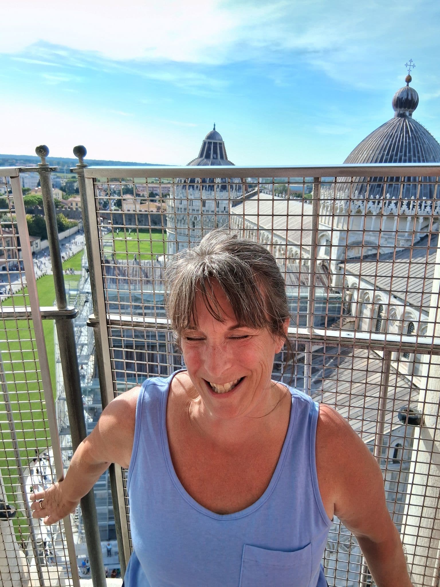 Leaning Tower of Pisa with a smiling woman leaning on a railing at the top, Piazza dei Miracoli, Pisa, Italy.