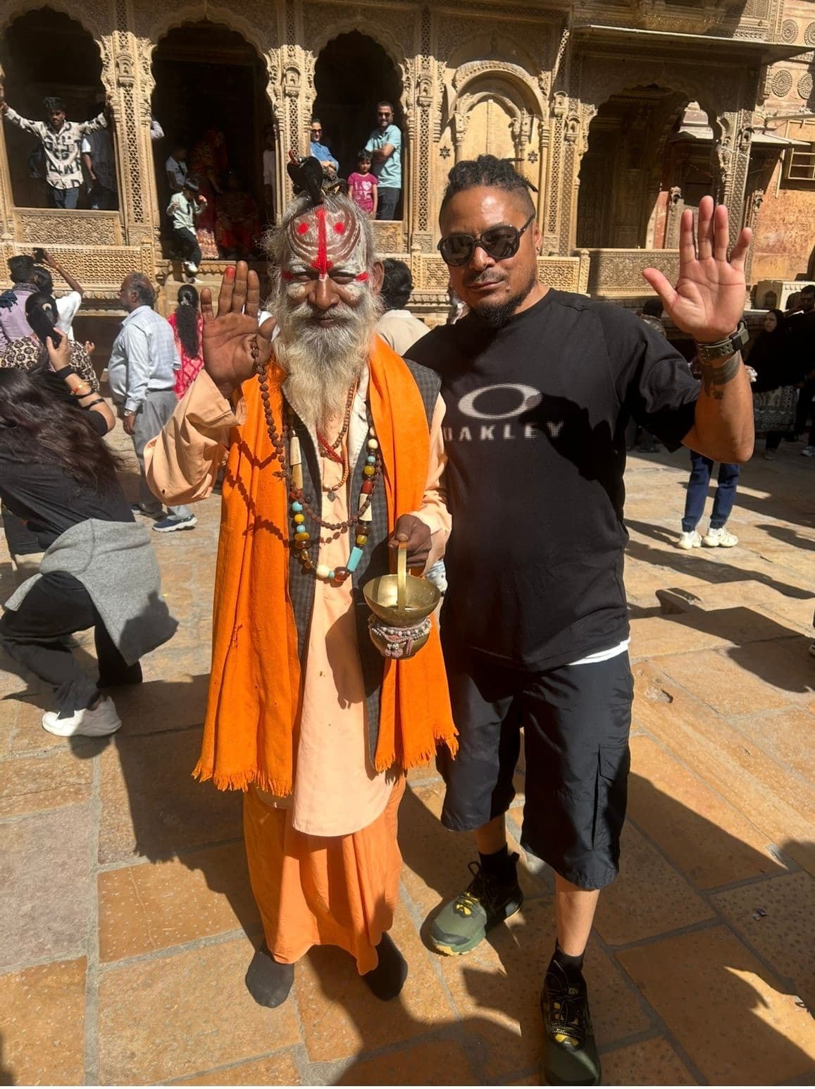 Patwon Ki Haveli façade with two men posing and raising their hands in Jaisalmer, India.