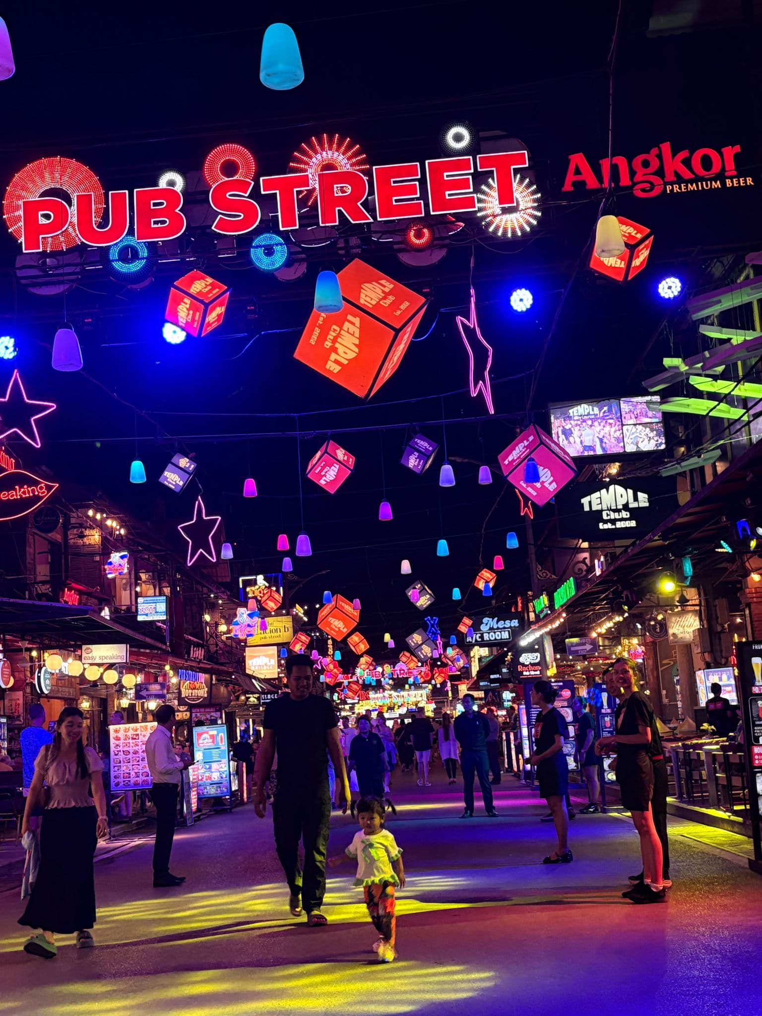 Pub Street neon sign and colorful hanging lights over people walking along a busy pedestrian street in Siem Reap, Cambodia.