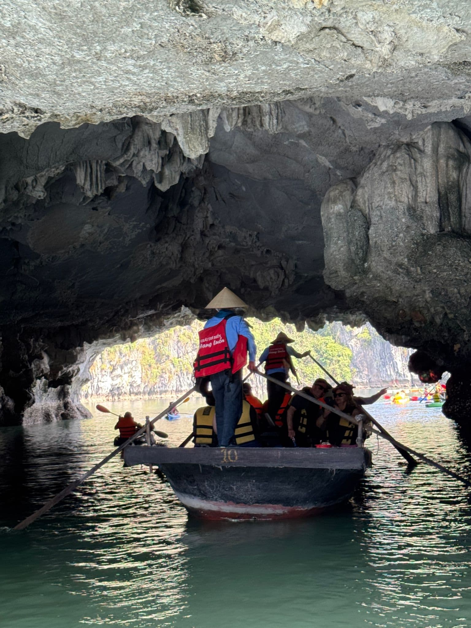 Rowboat of travelers passing under a limestone cave in Ha Long Bay, Vietnam.