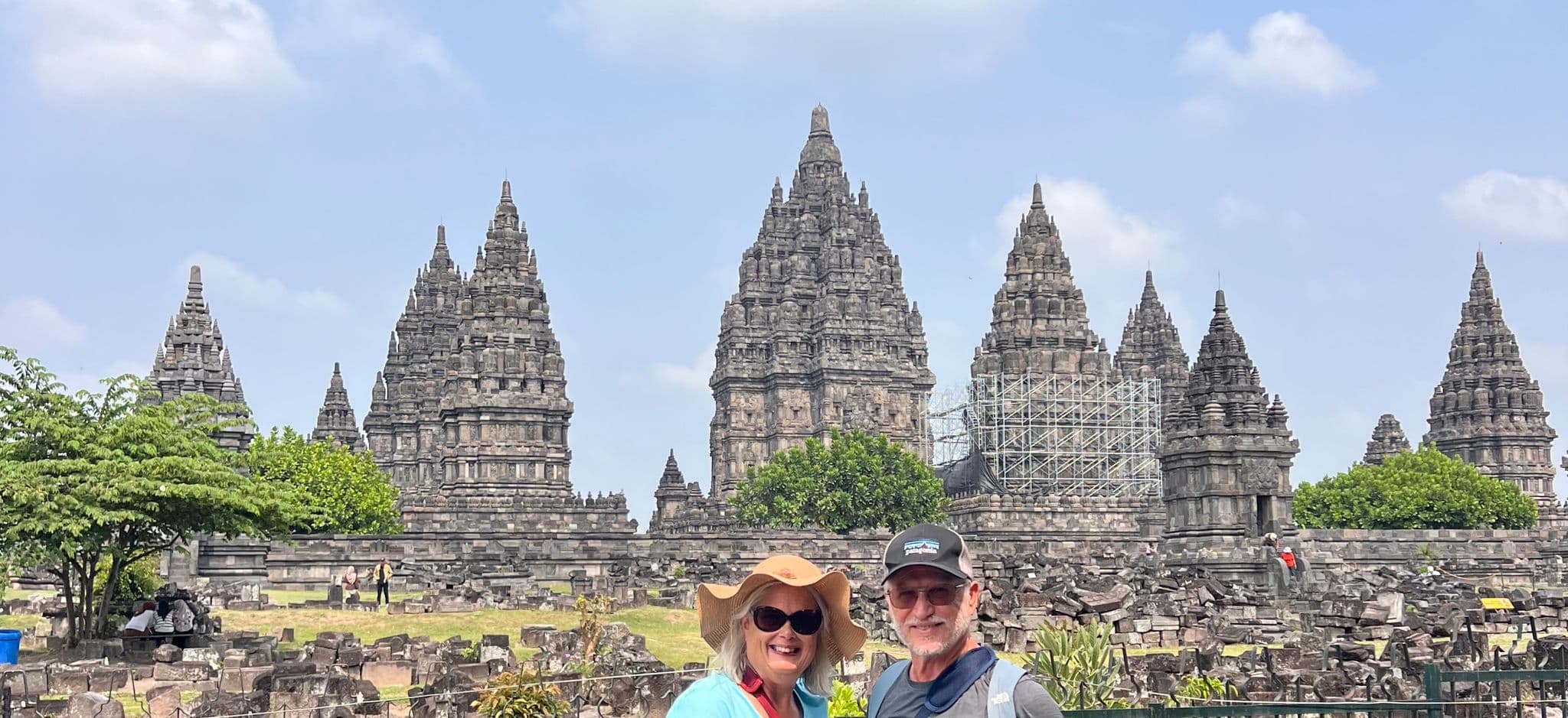 Prambanan Temple with two travelers smiling and posing in front, near Yogyakarta, Indonesia.