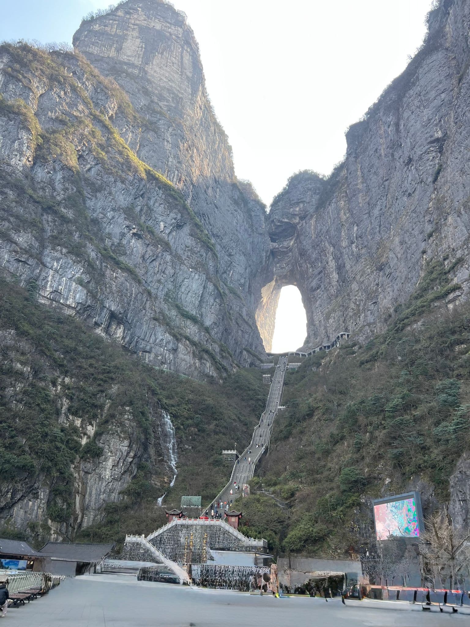 Tianmen Cave natural arch with a long stone stairway and people climbing up Tianmen Mountain, Zhangjiajie, China