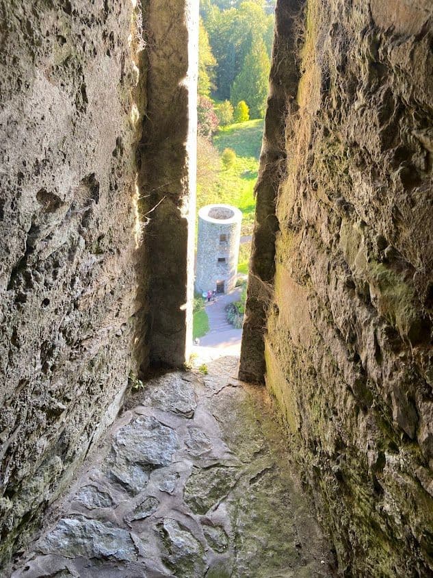 Blarney Castle tower seen through a narrow stone window, looking down to the gardens in Blarney, Ireland.
